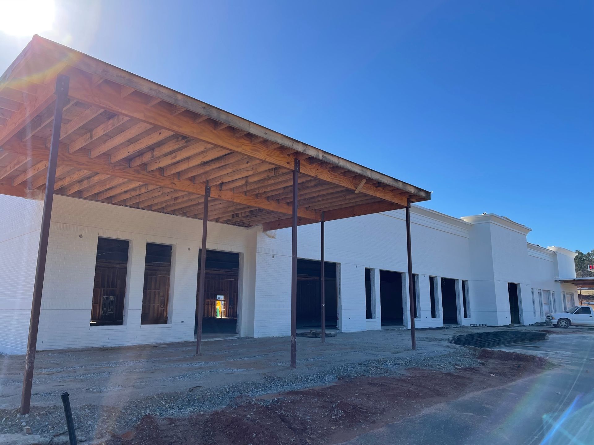 A white building under construction with a wooden roof.