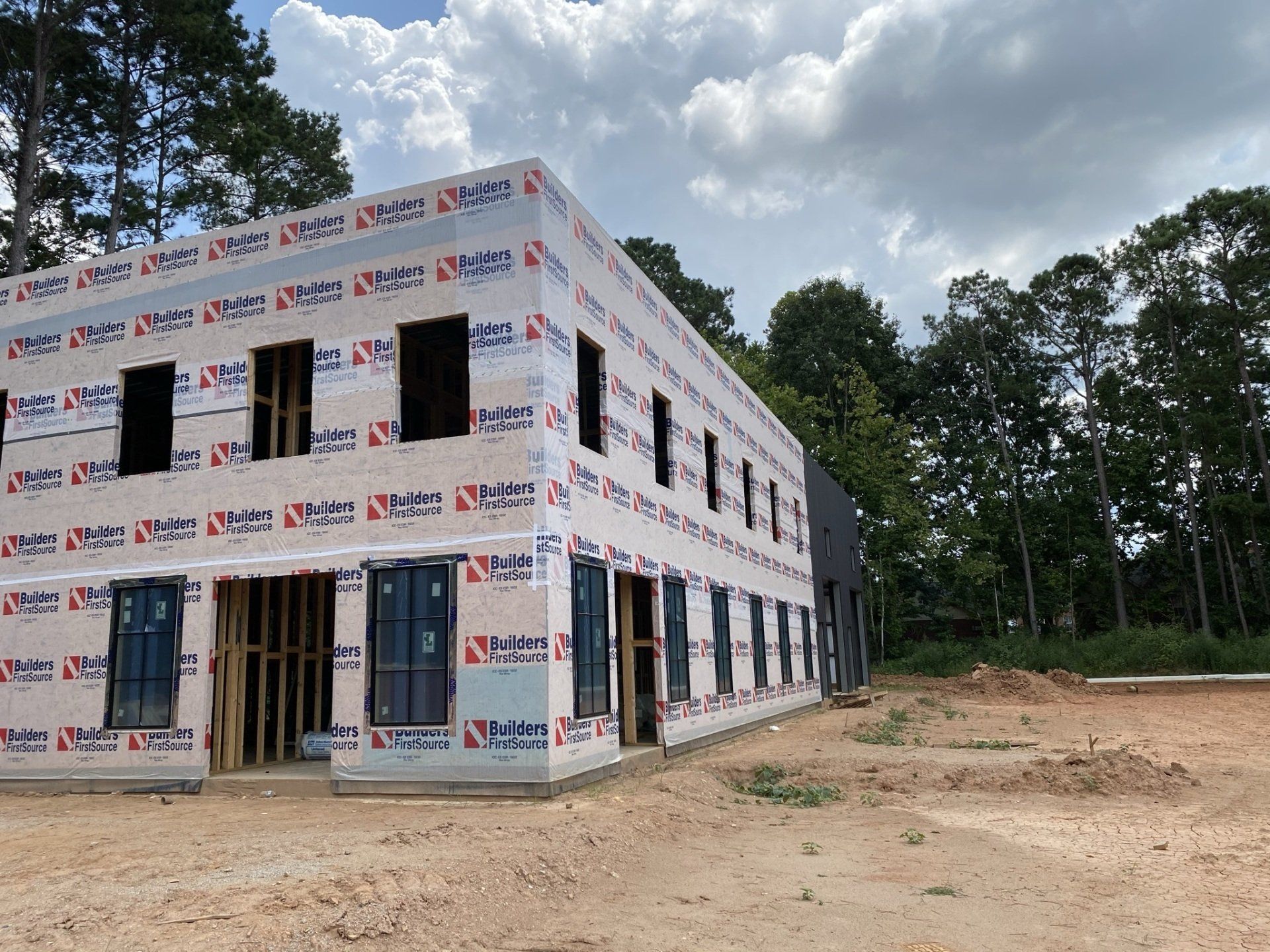 A large building is being built in the middle of a dirt field.