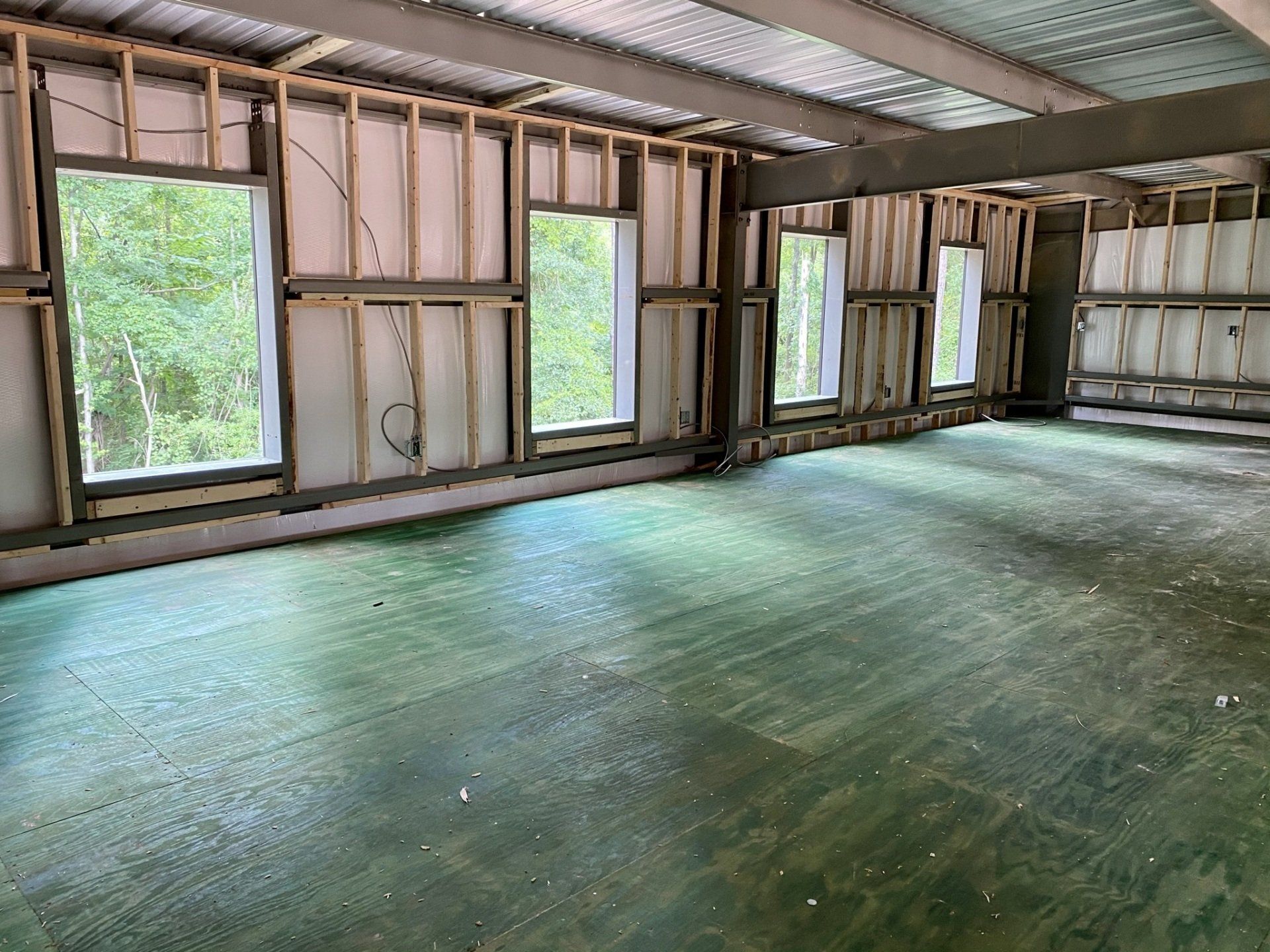 An empty room with a green floor and a lot of windows.