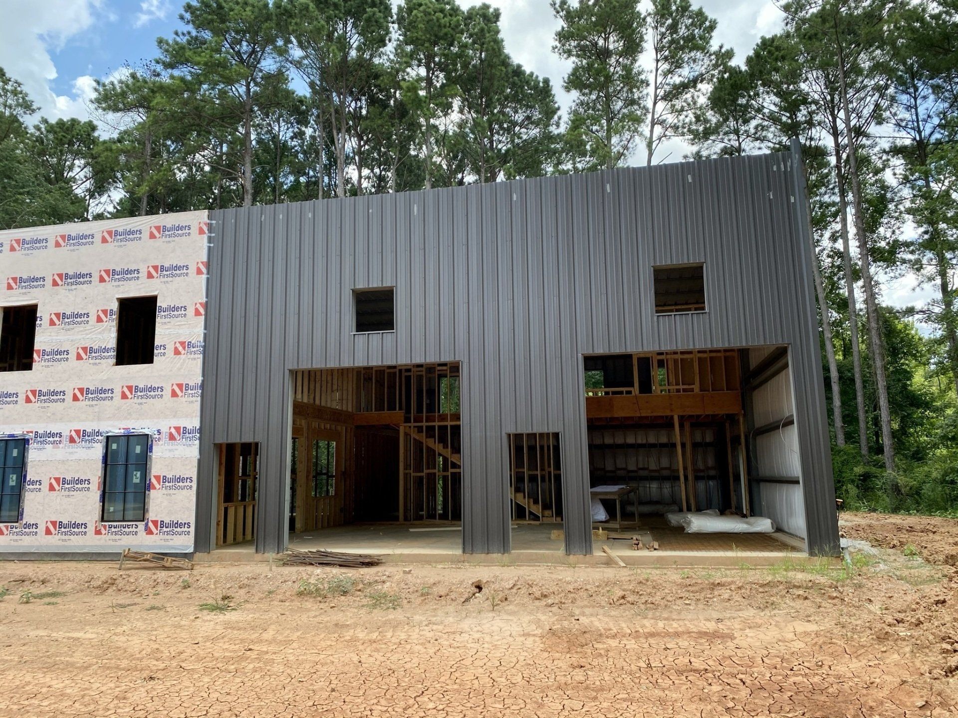 A large building is being built in a field with trees in the background.