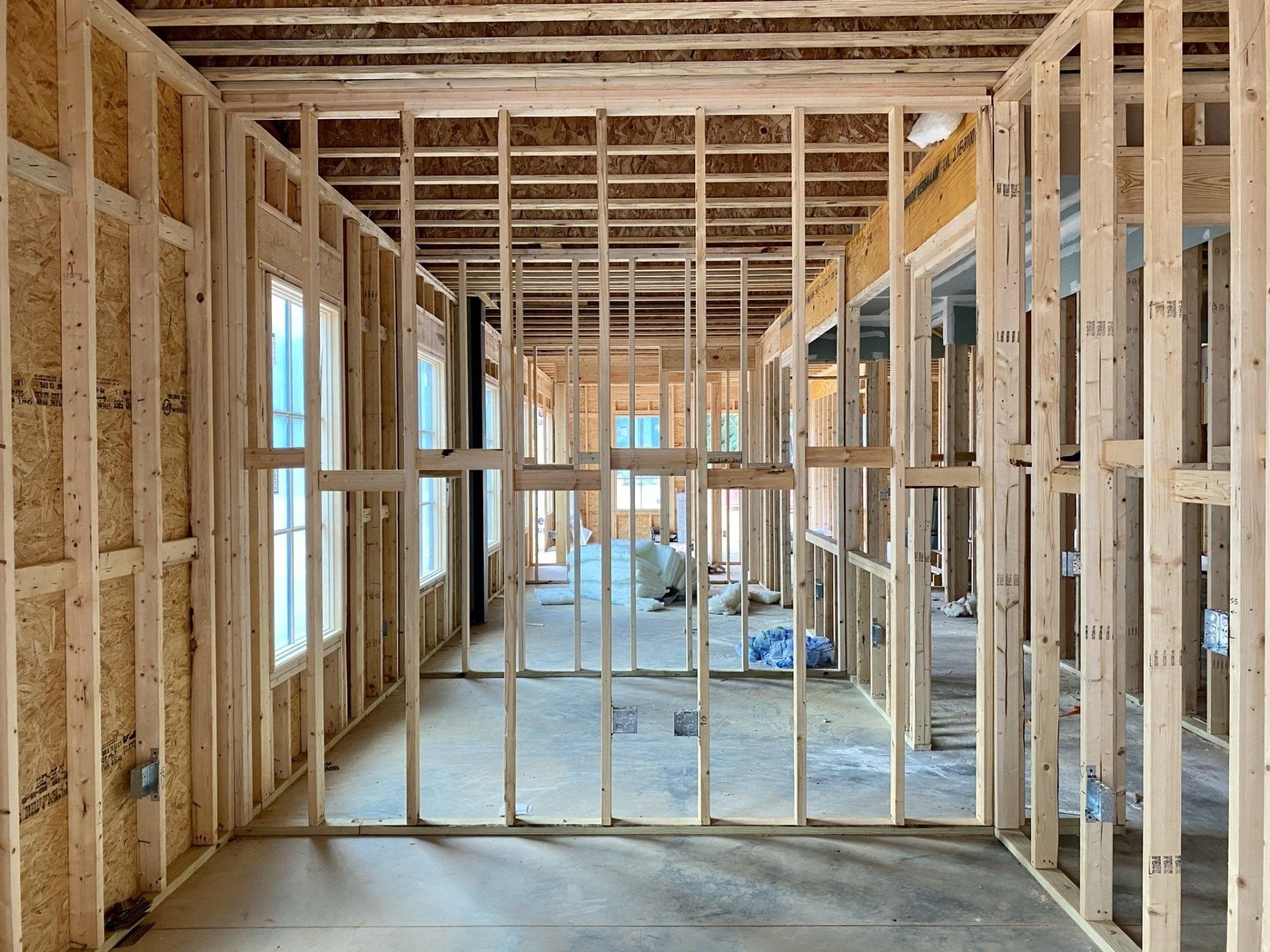The inside of a house under construction with wooden beams and windows.