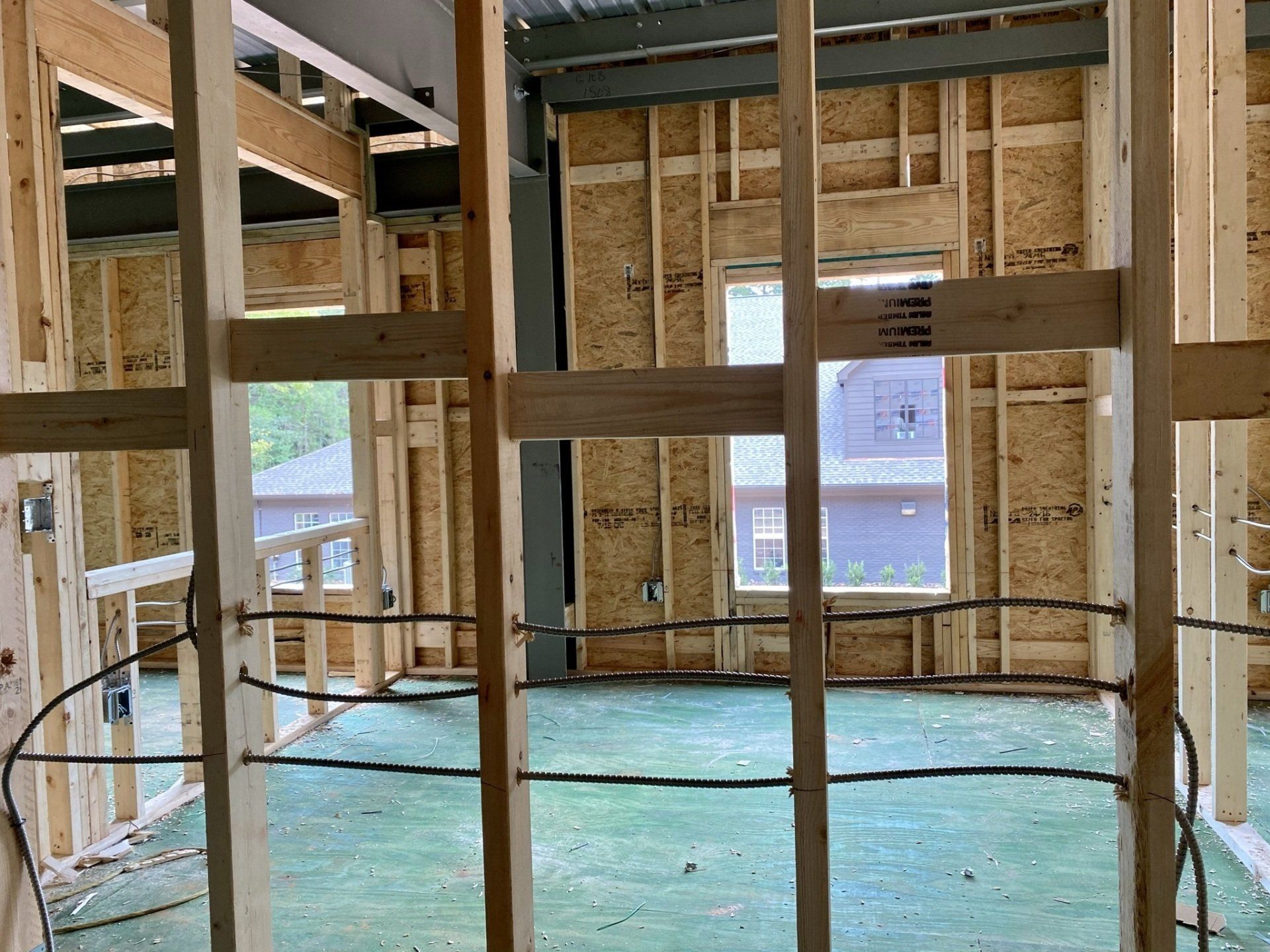 The inside of a building under construction with wooden beams and a green floor.