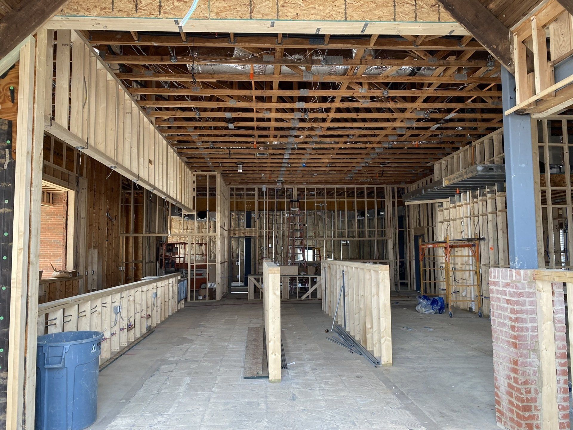The inside of a building under construction with a blue trash can in the middle.