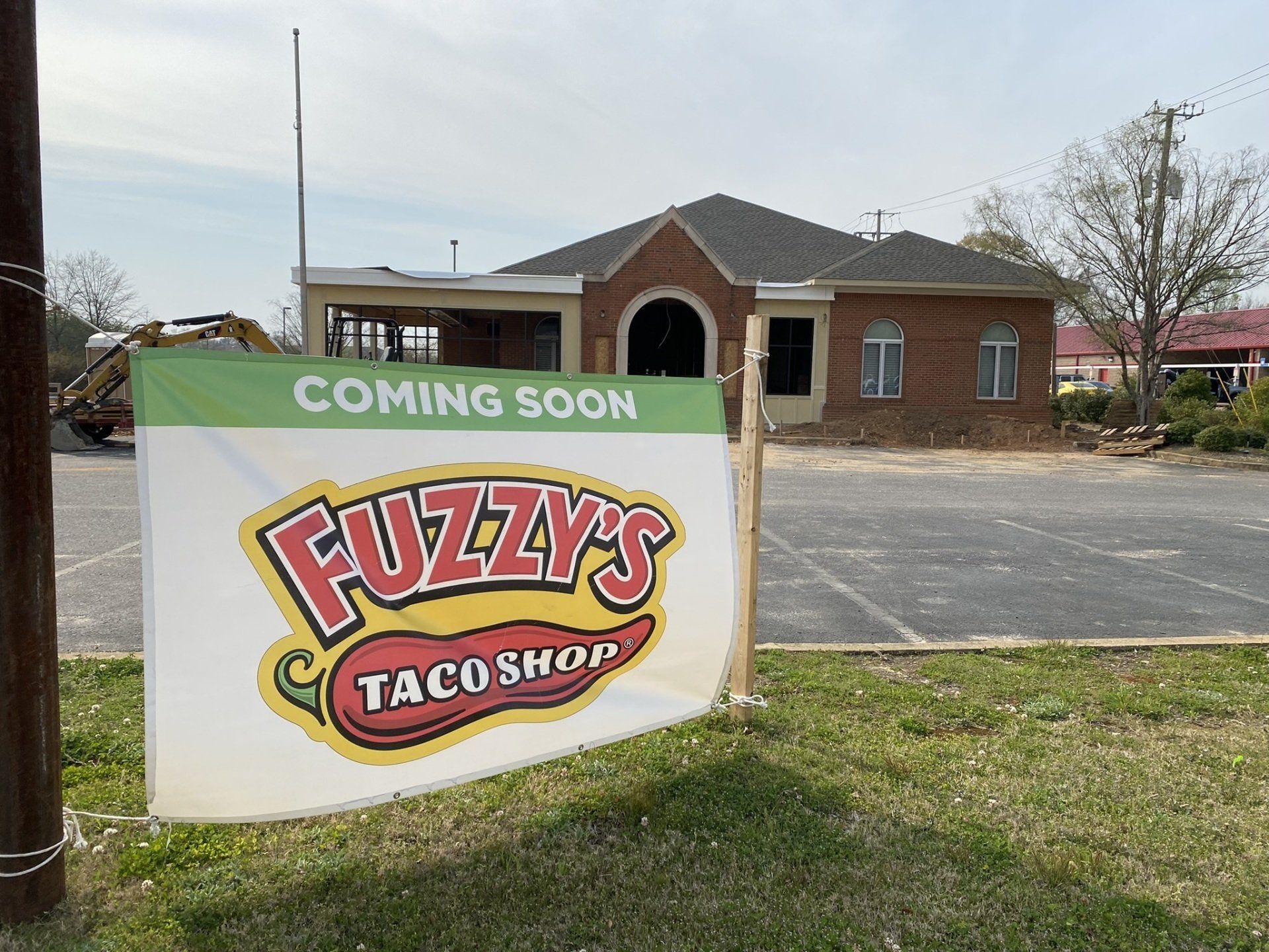 A sign for fuzzy 's taco shop is sitting in front of a brick building.