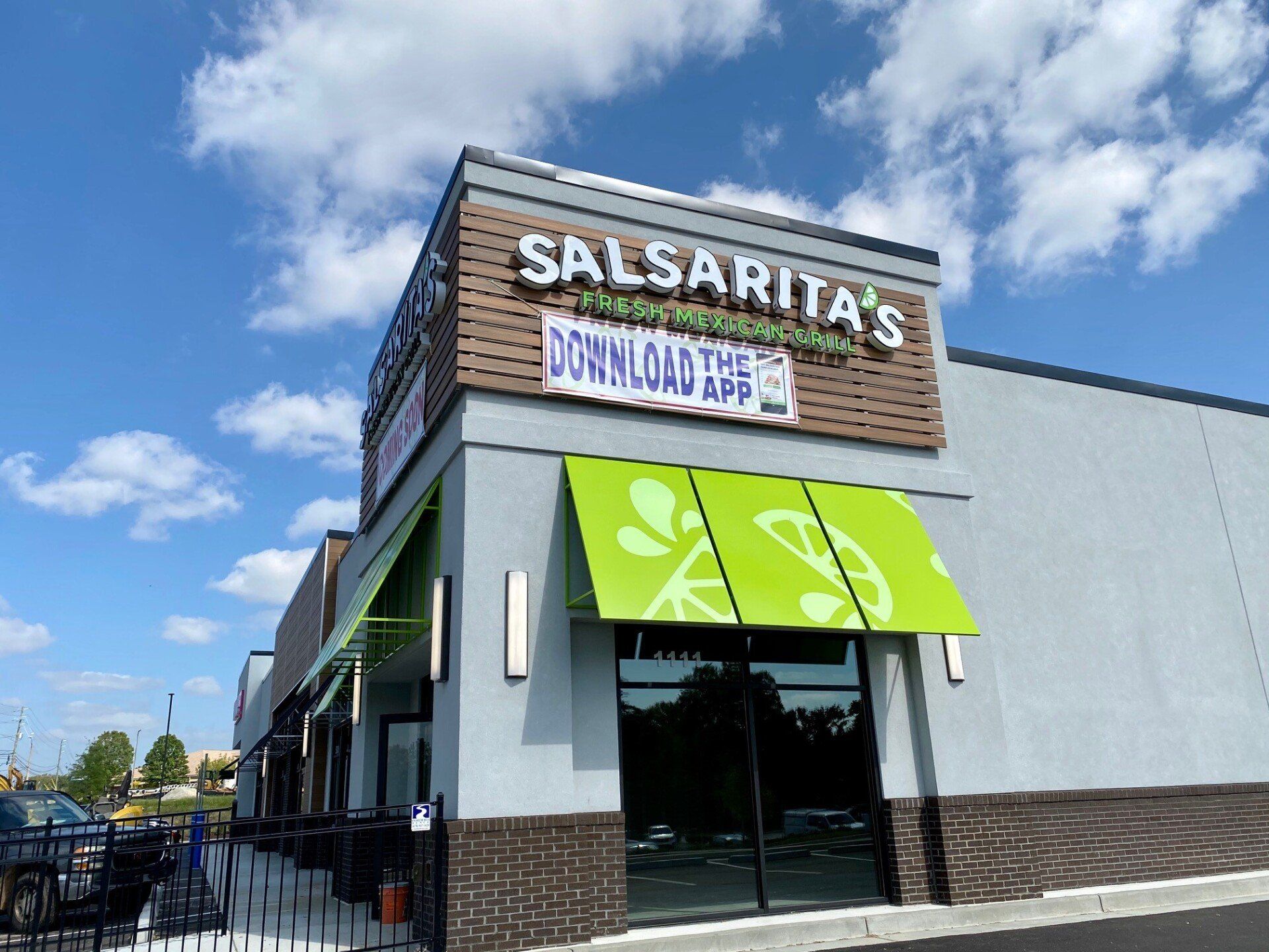 The front of a salsarita 's restaurant with a green awning.