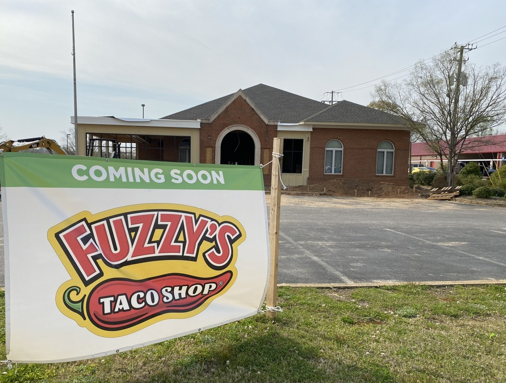 A fuzzy 's taco shop sign is sitting in front of a brick building.