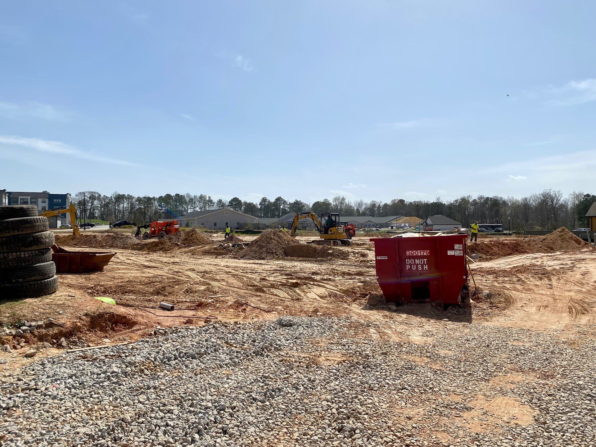A construction site with a red dumpster in the middle of it.