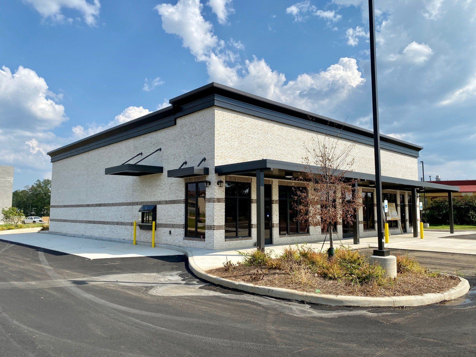 A white building with a black roof is sitting on the side of a road.