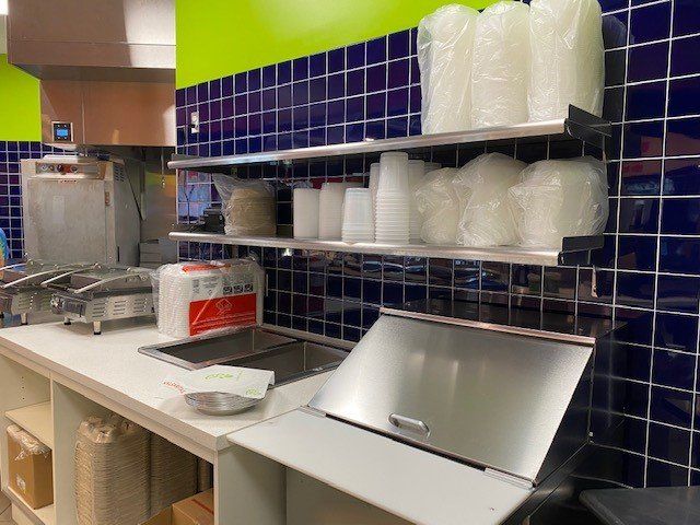 A kitchen with a sink and shelves filled with plastic containers.