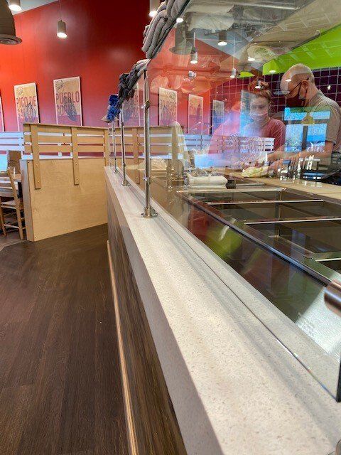 A man in a red shirt is standing behind a counter in a restaurant.