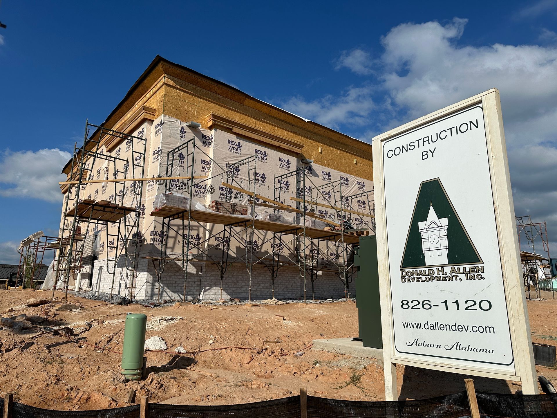A construction sign is in front of a building under construction
