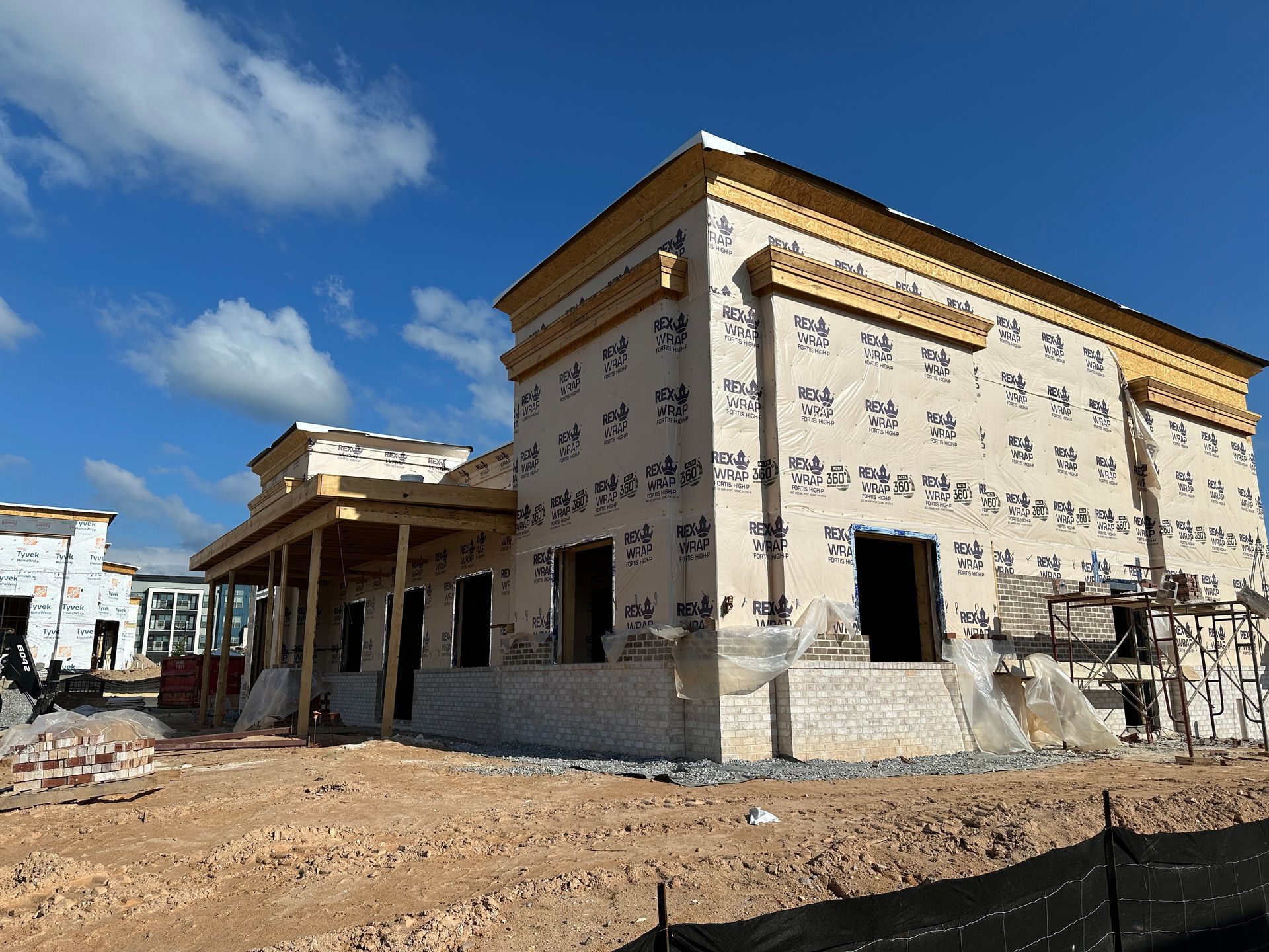 A large building is being built in the middle of a dirt field.