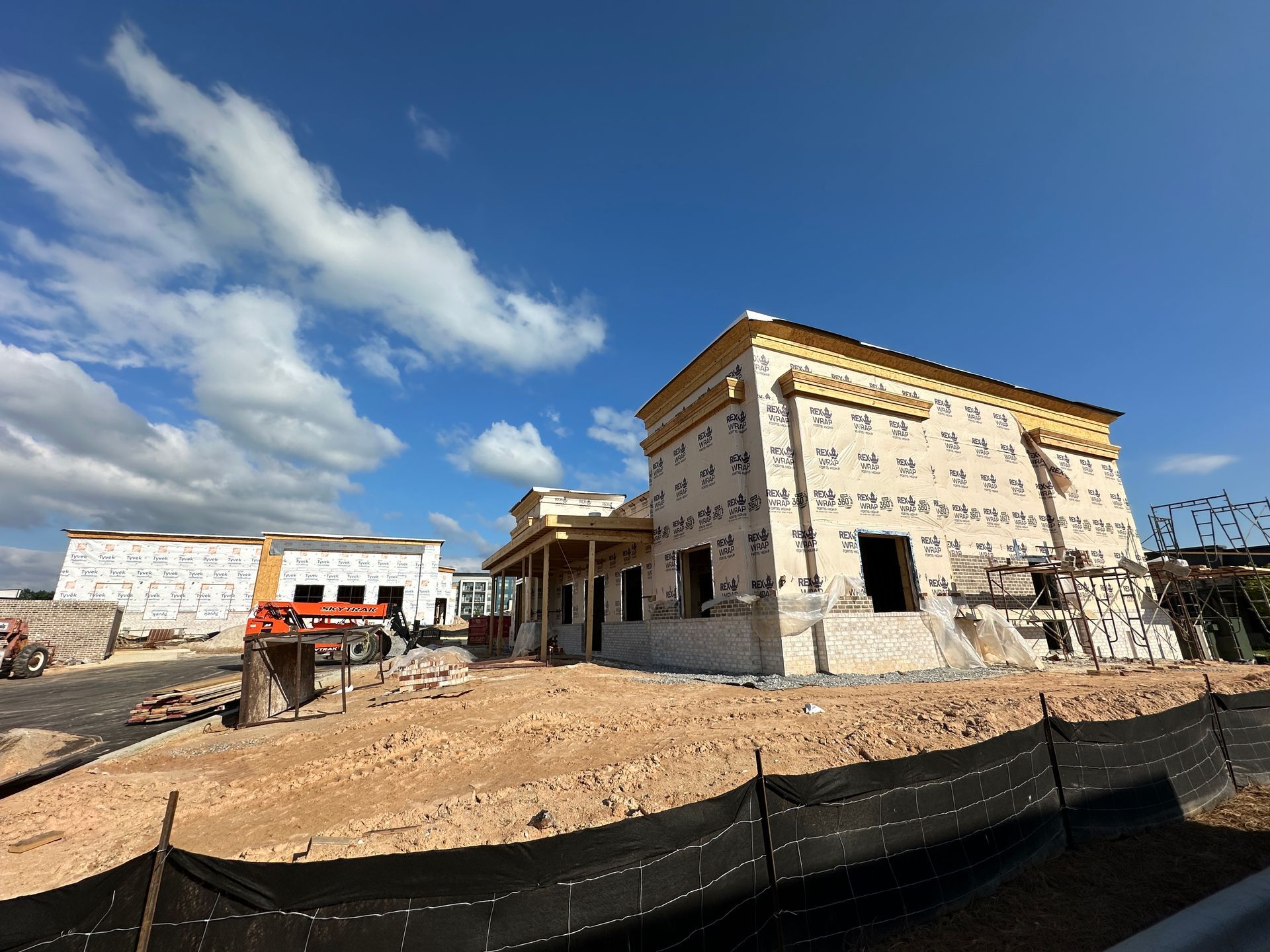A large building is being built in the middle of a dirt field.