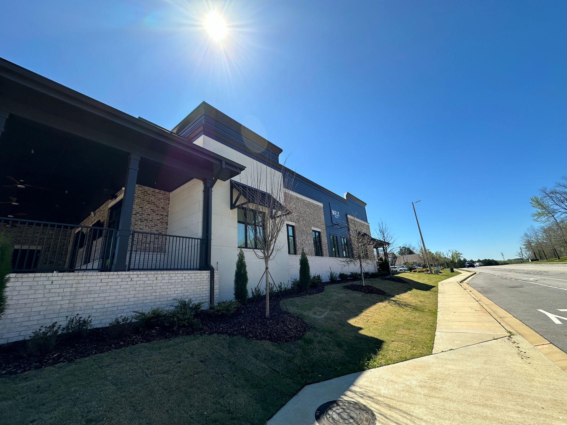 A large building with a porch and a sidewalk in front of it.