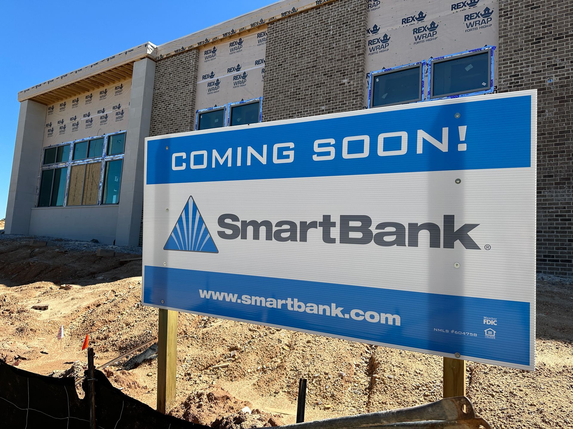 A coming soon sign for smartbank is in front of a building under construction