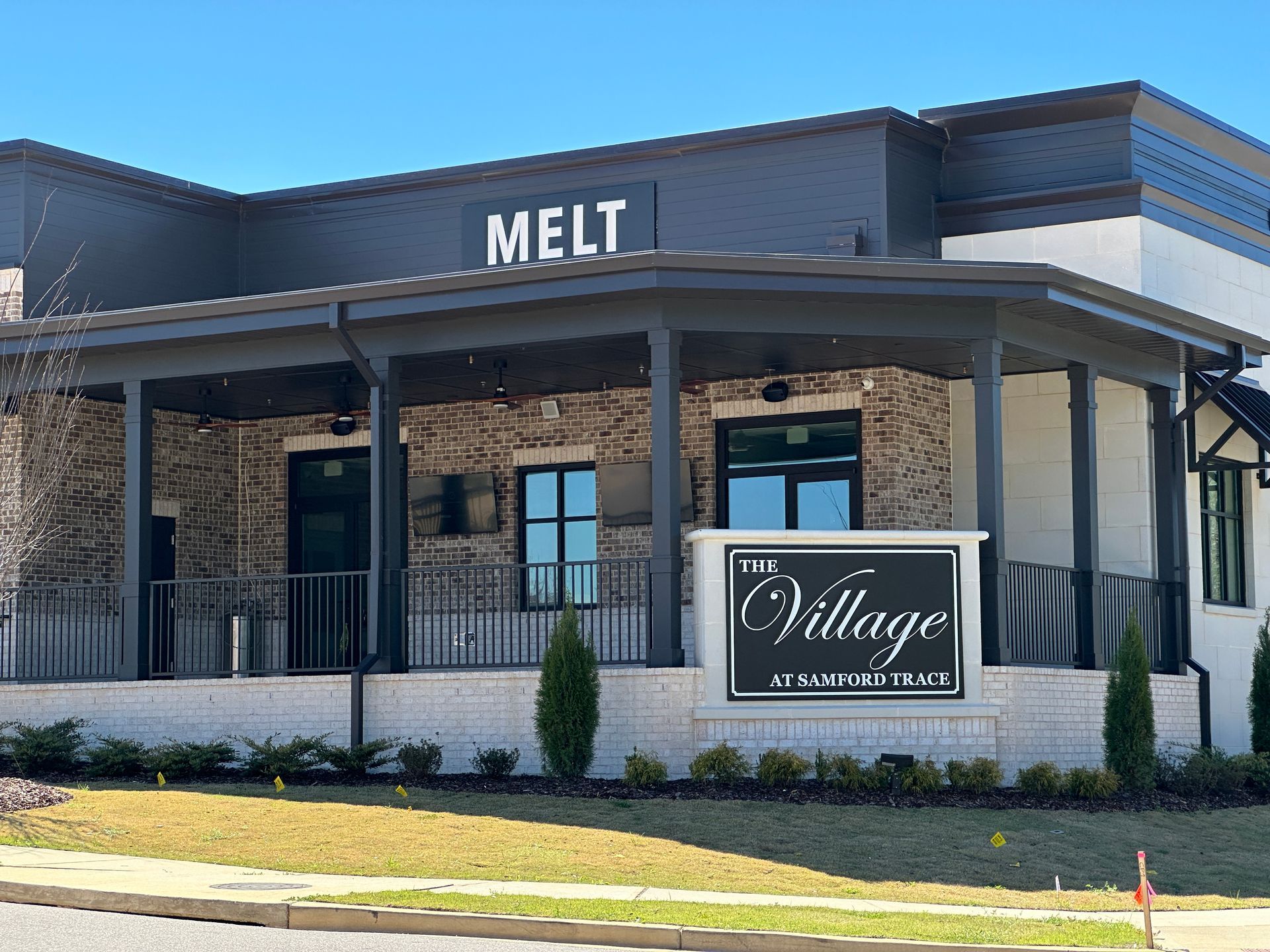 A large building with a porch and a sign that says melt village.