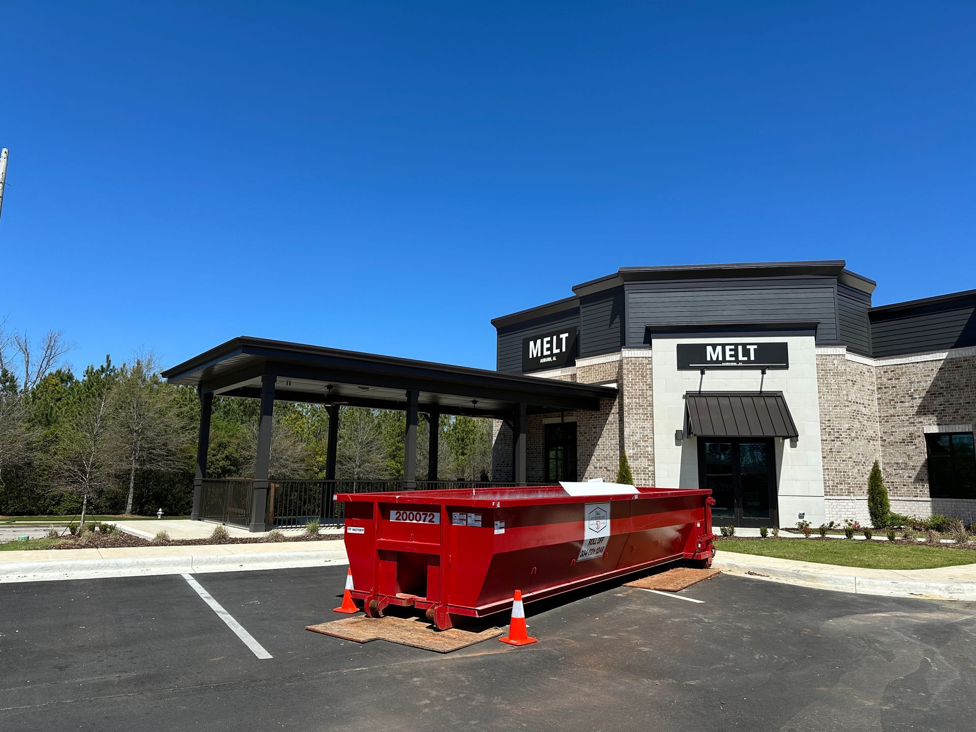 A large red dumpster is parked in front of a building.