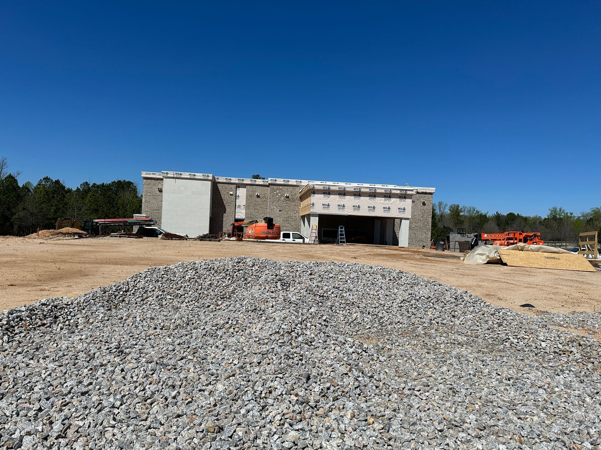 A large building under construction with a pile of gravel in front of it.