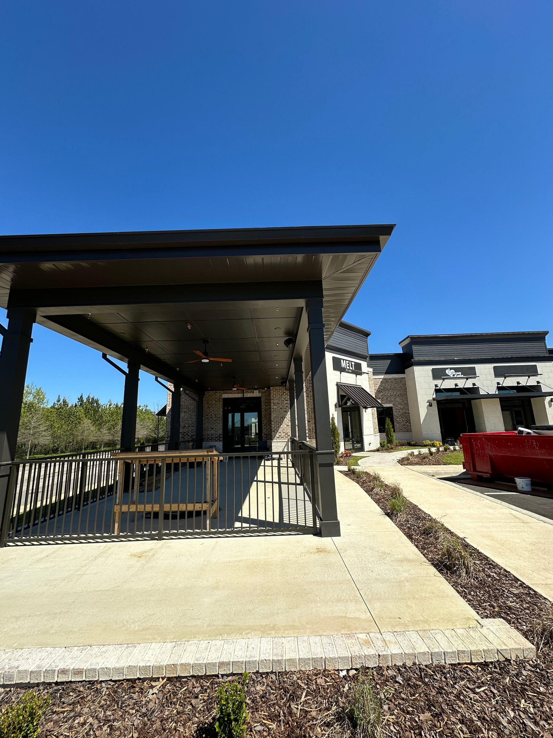 A large building with a covered porch and a red truck parked in front of it.