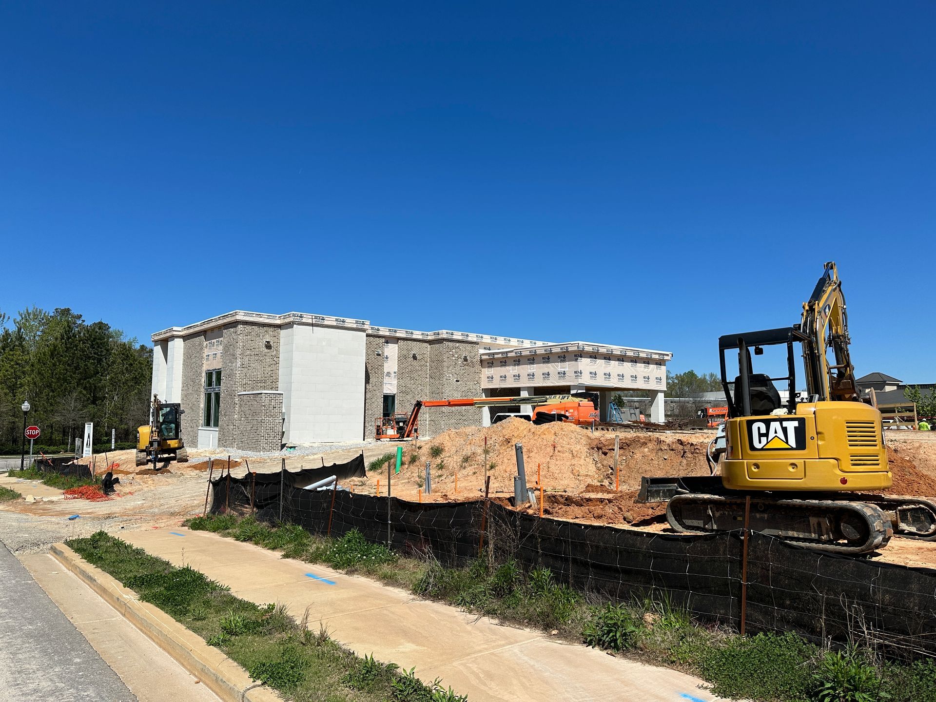 A cat excavator is parked in front of a building under construction.