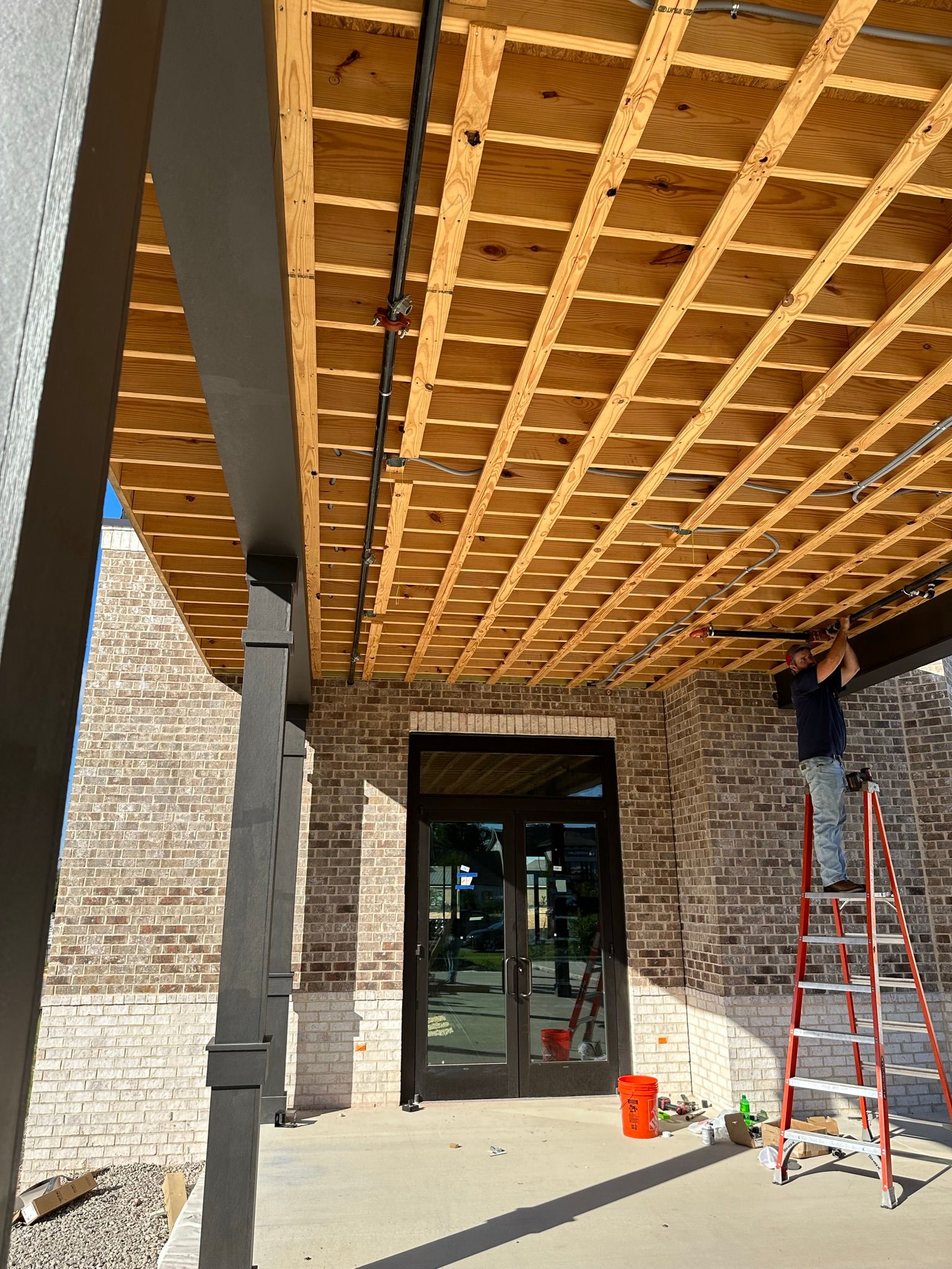 A man is standing on a ladder under a wooden ceiling.