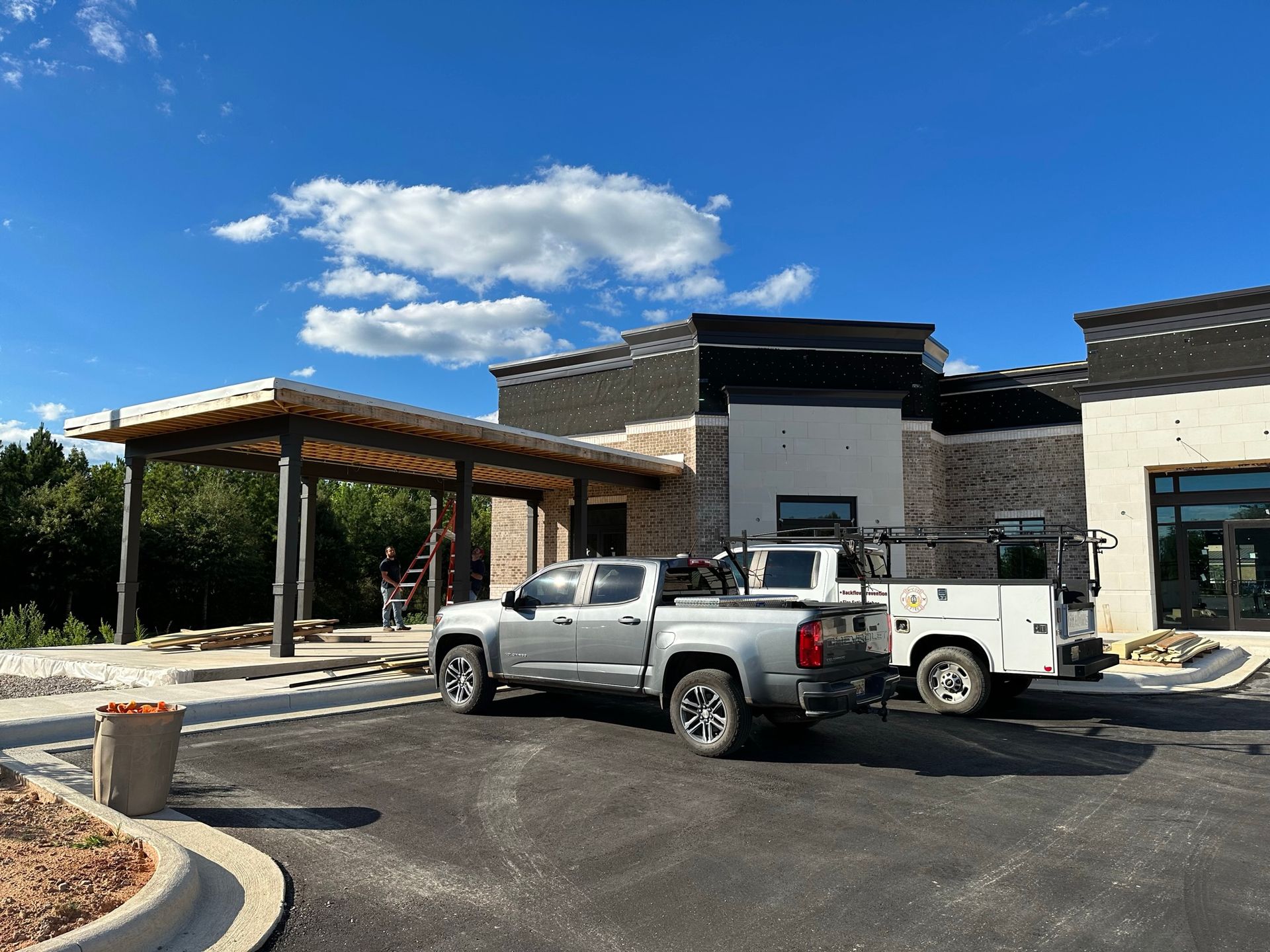 Two trucks are parked in front of a building under construction.