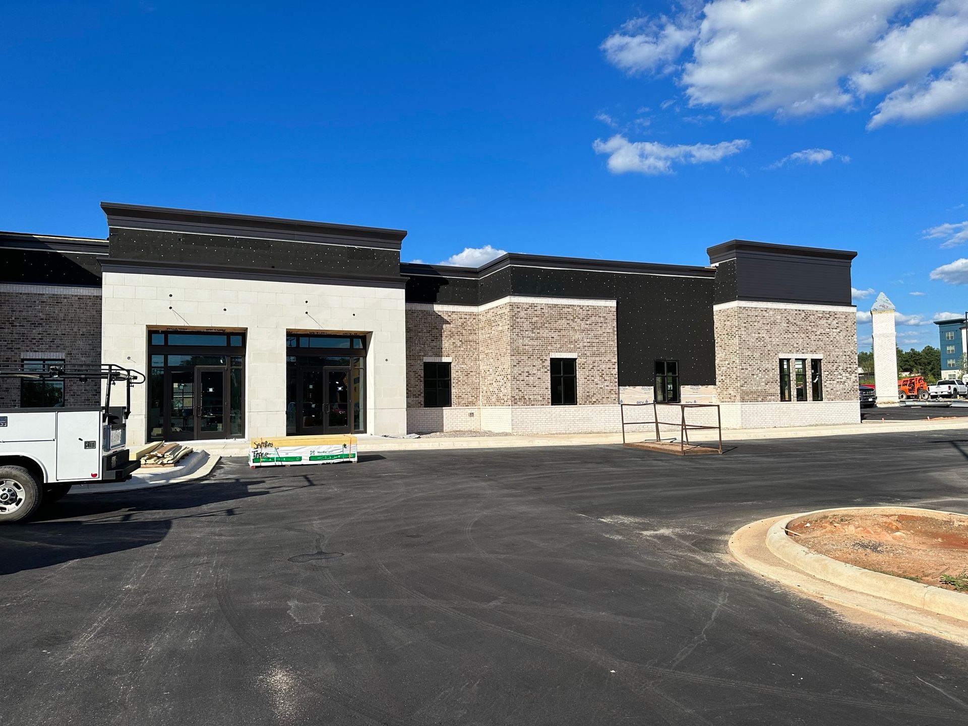 A white truck is parked in front of a building under construction.