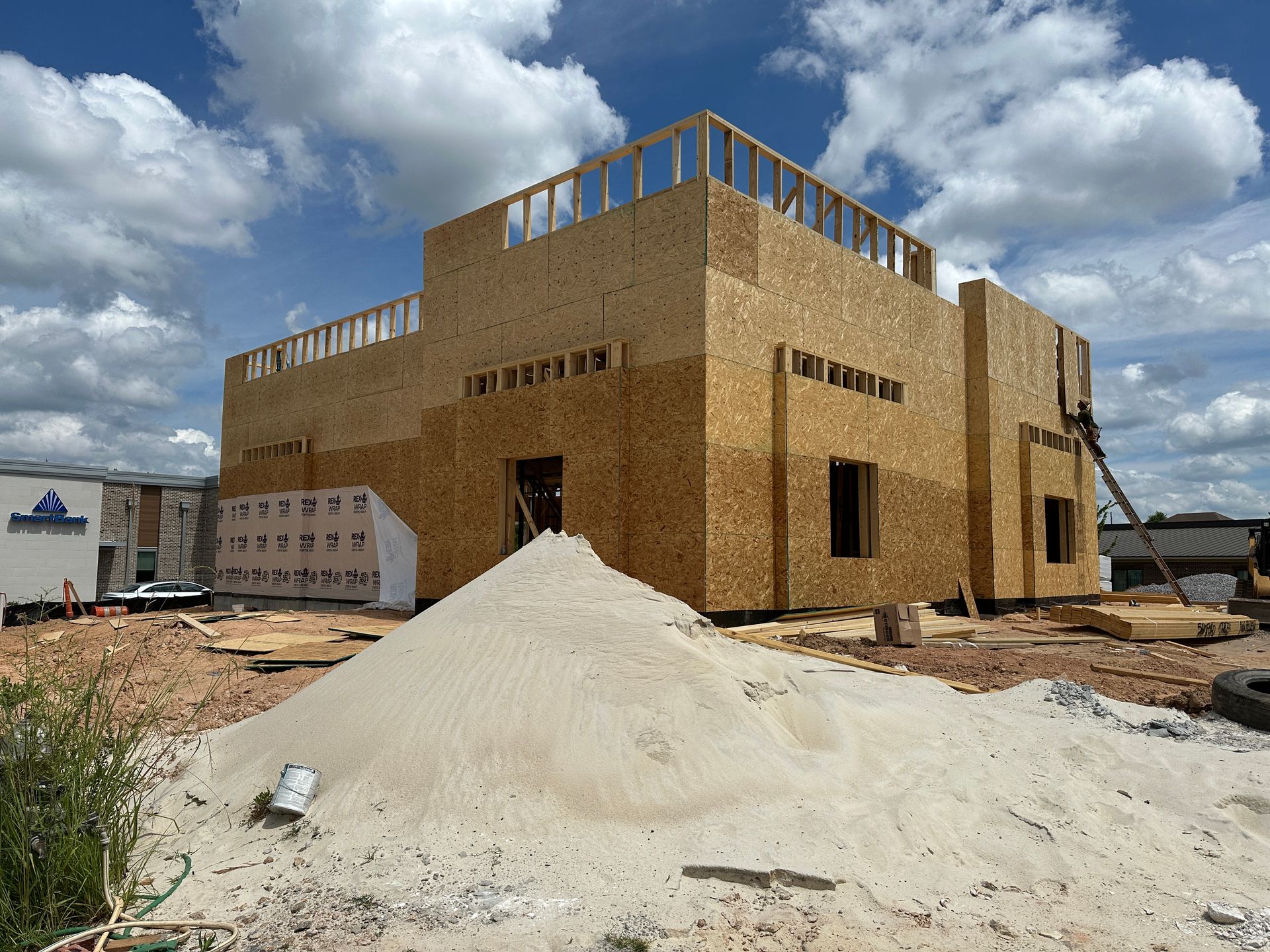 A large building under construction with a pile of sand in front of it.