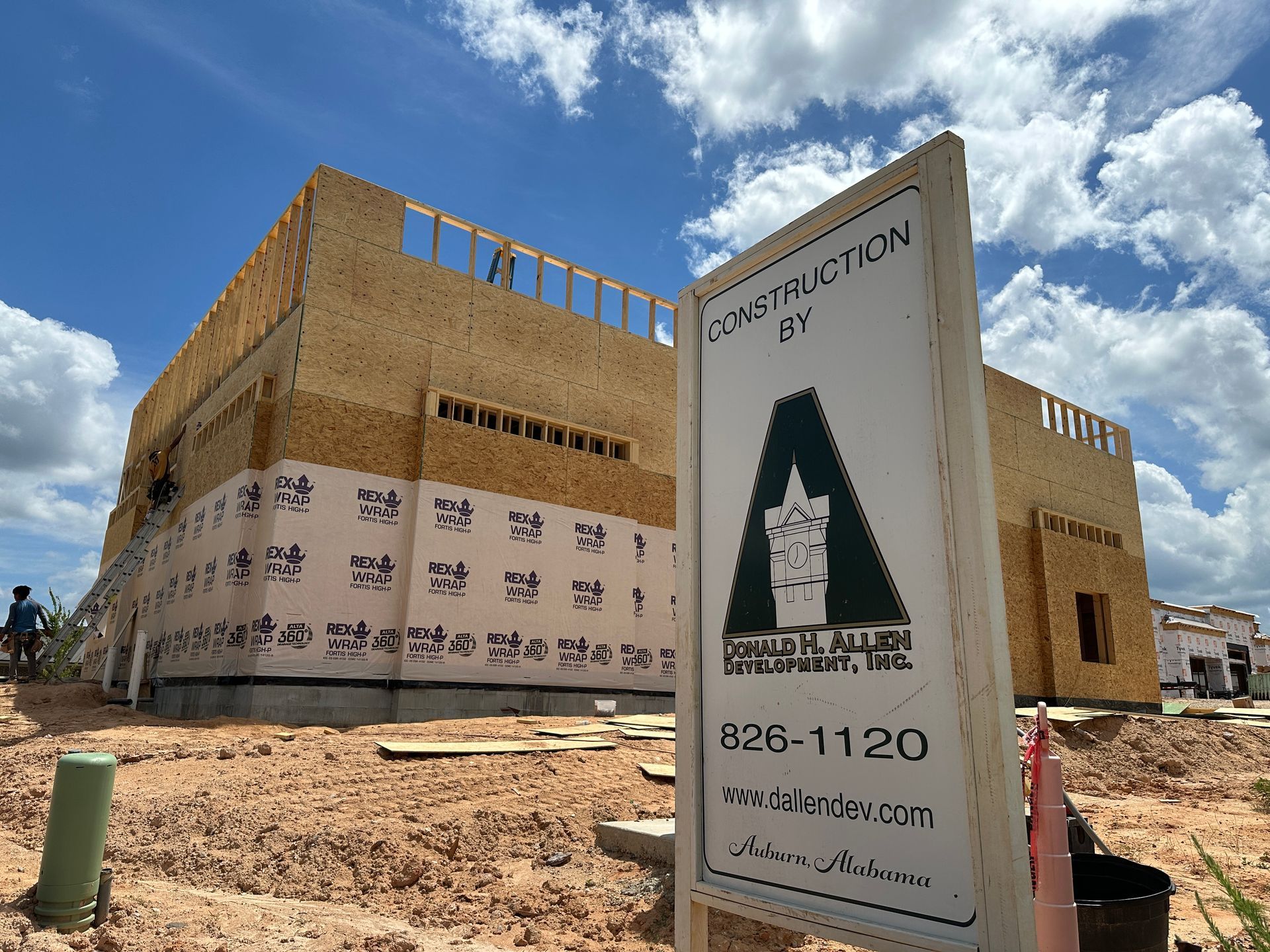 A construction sign is sitting in front of a building under construction.