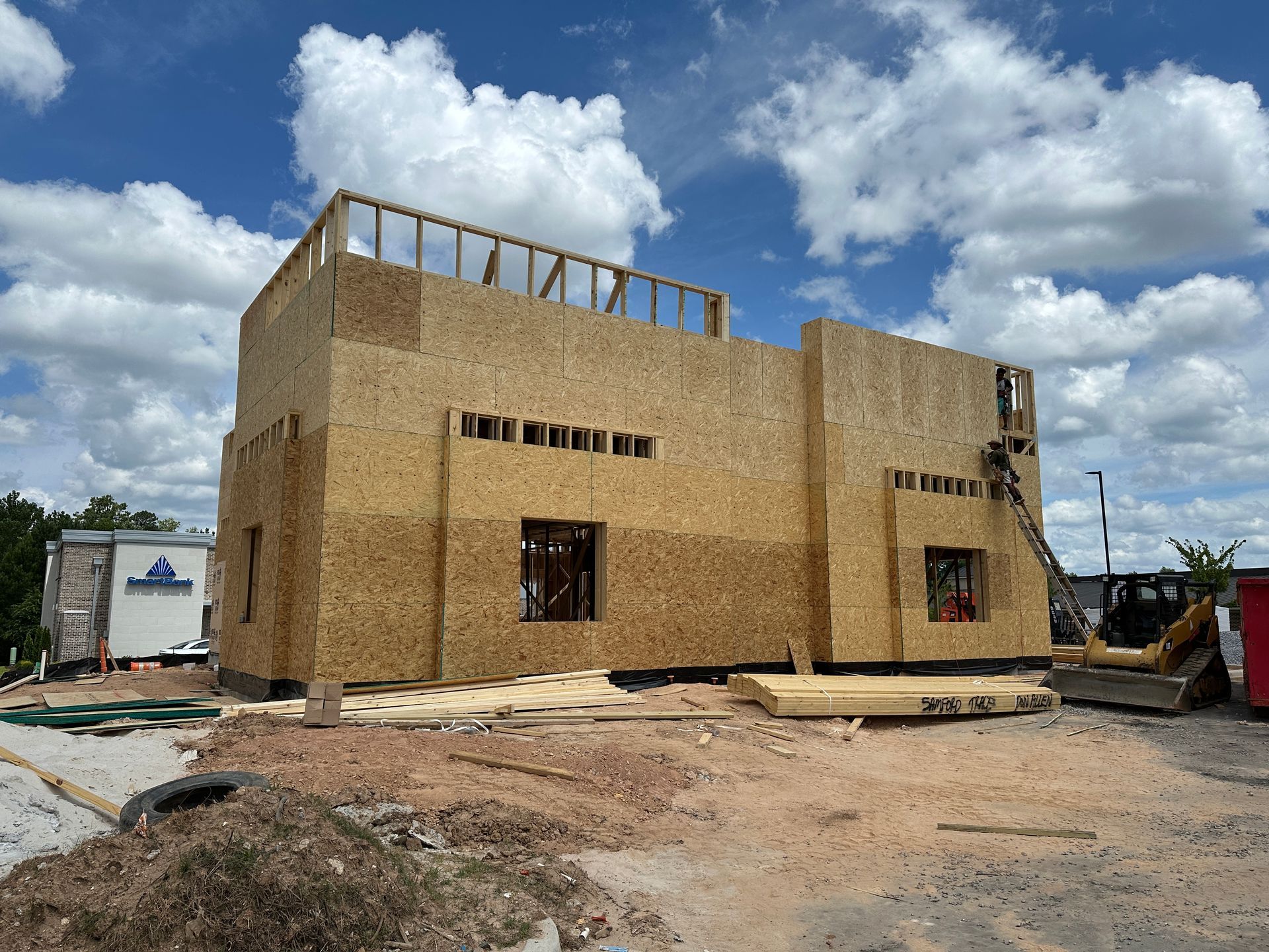 A large wooden building is being built on a dirt field.
