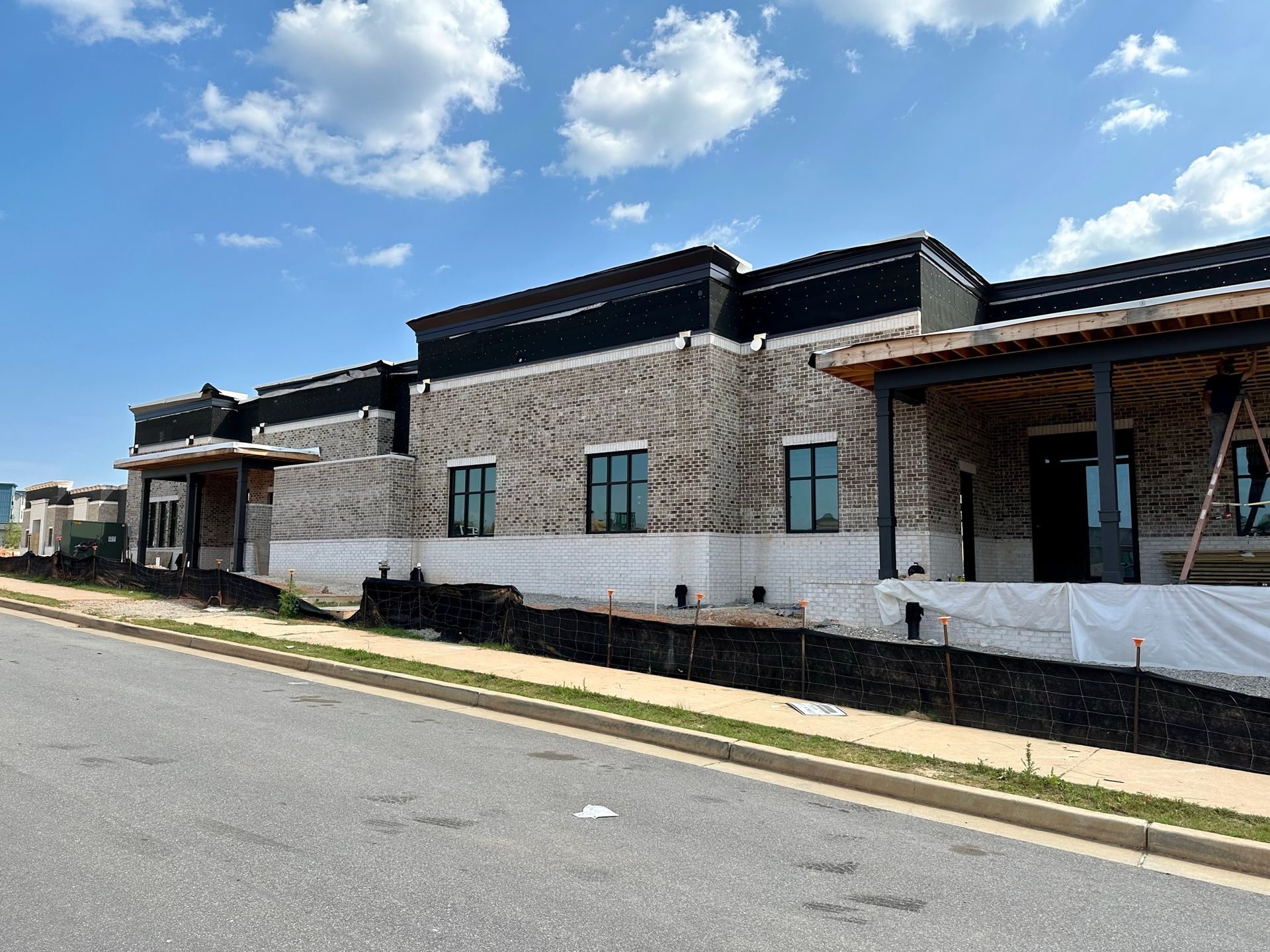 A large brick building is being built on the side of the road.