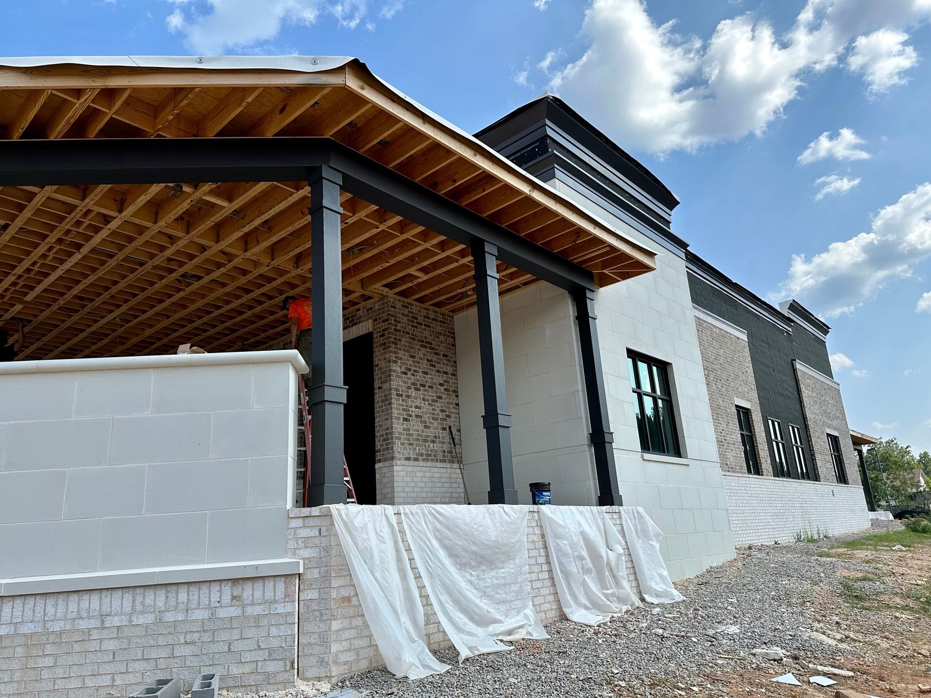 A building under construction with a porch and a blue sky in the background.