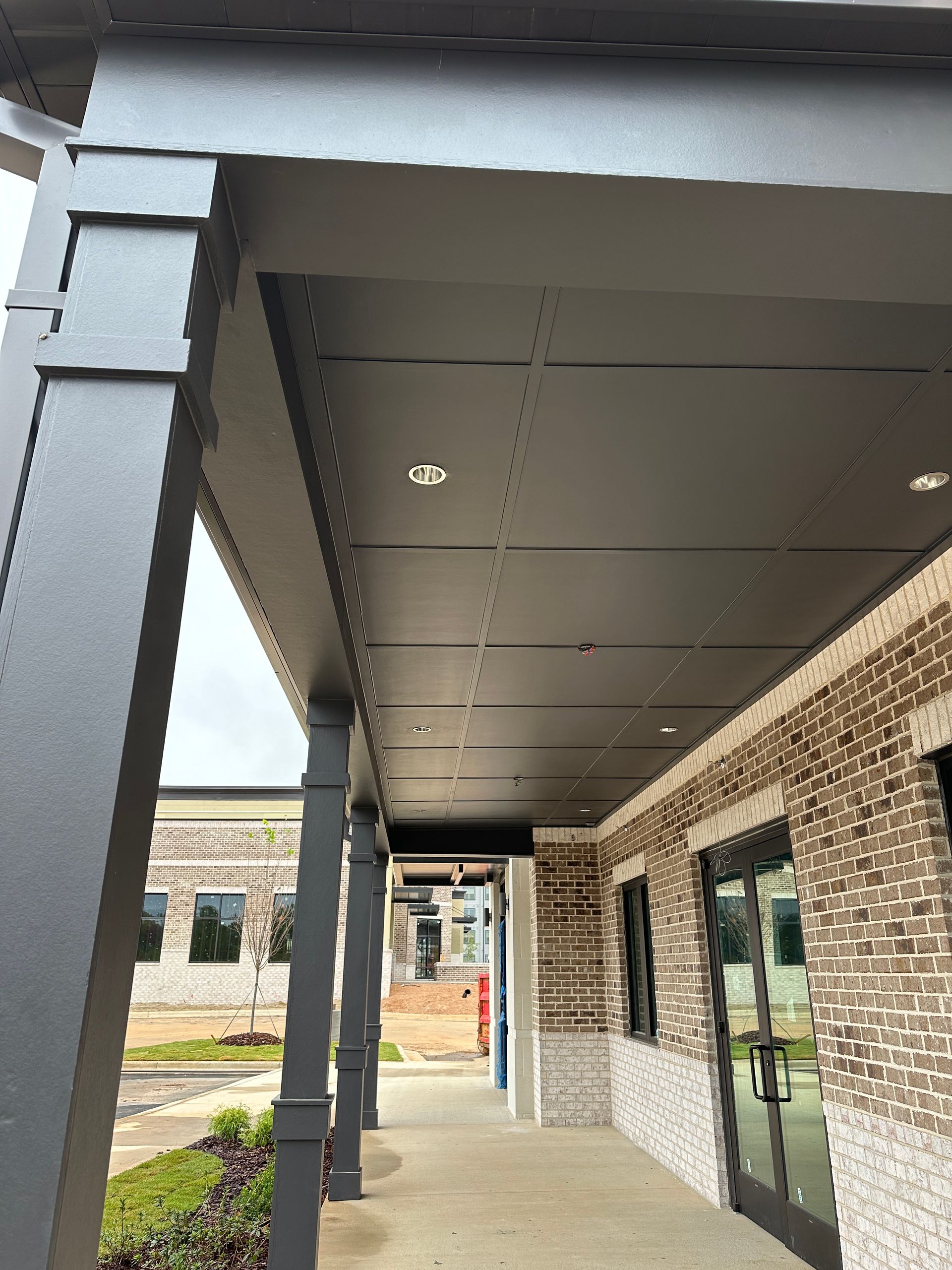 A brick building with a porch and a black roof.