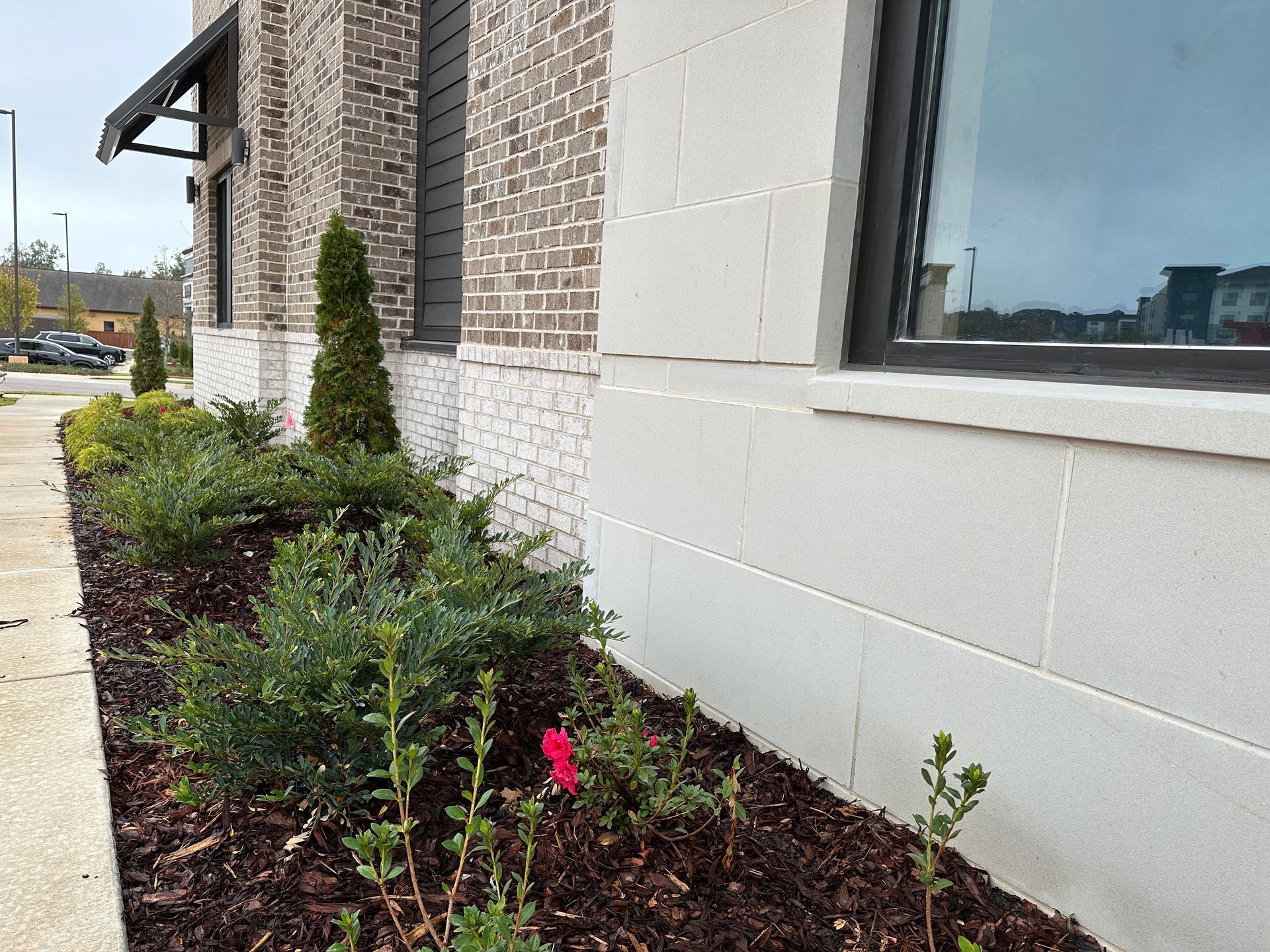 A brick building with a flower bed in front of it.
