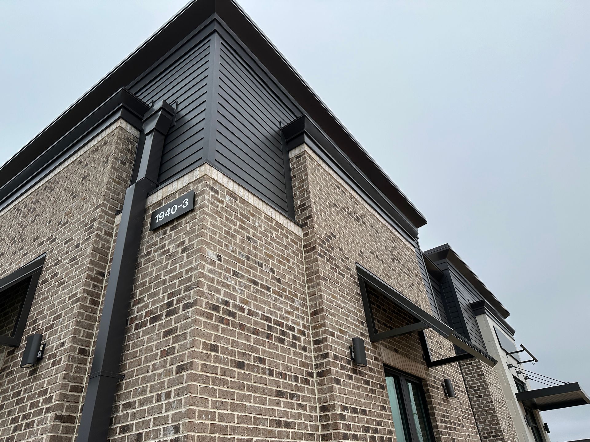 A brick building with a black gutter on the side of it.