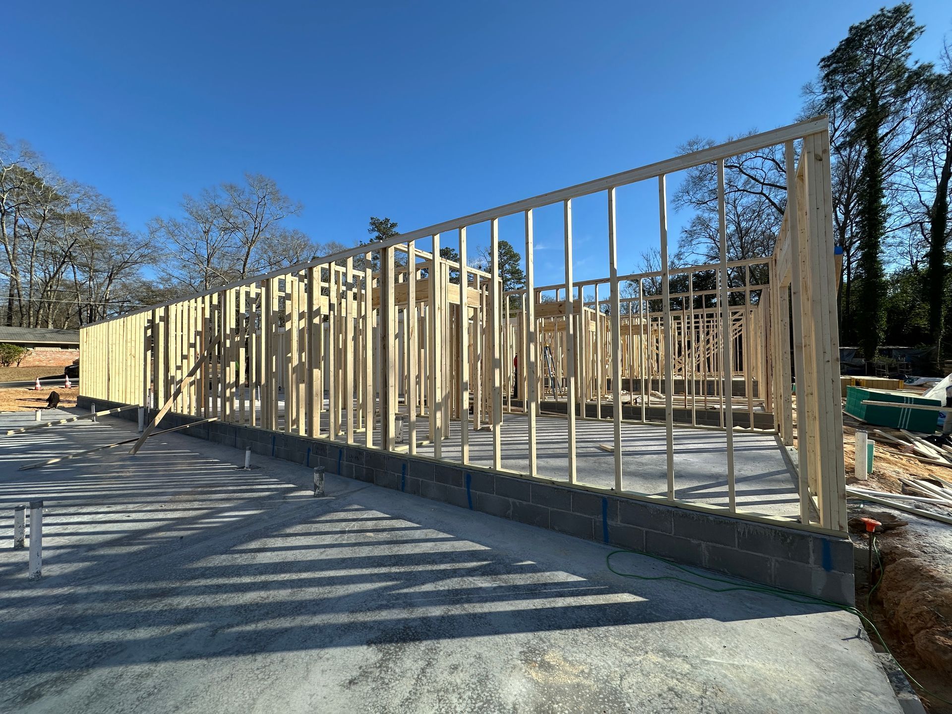 Wood frame construction of a building on concrete foundation, outdoors on a sunny day.