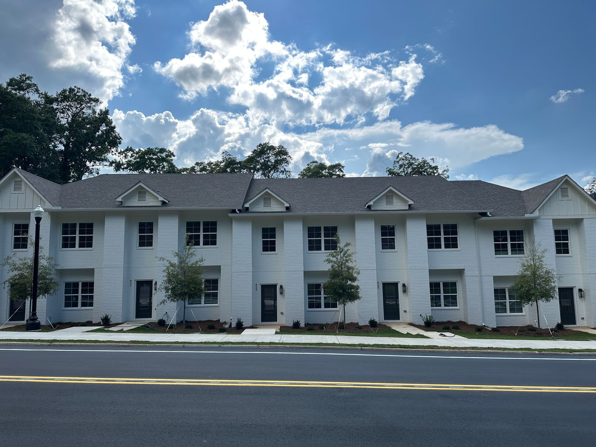 White two-story apartment building with gray roof under a partly cloudy sky.