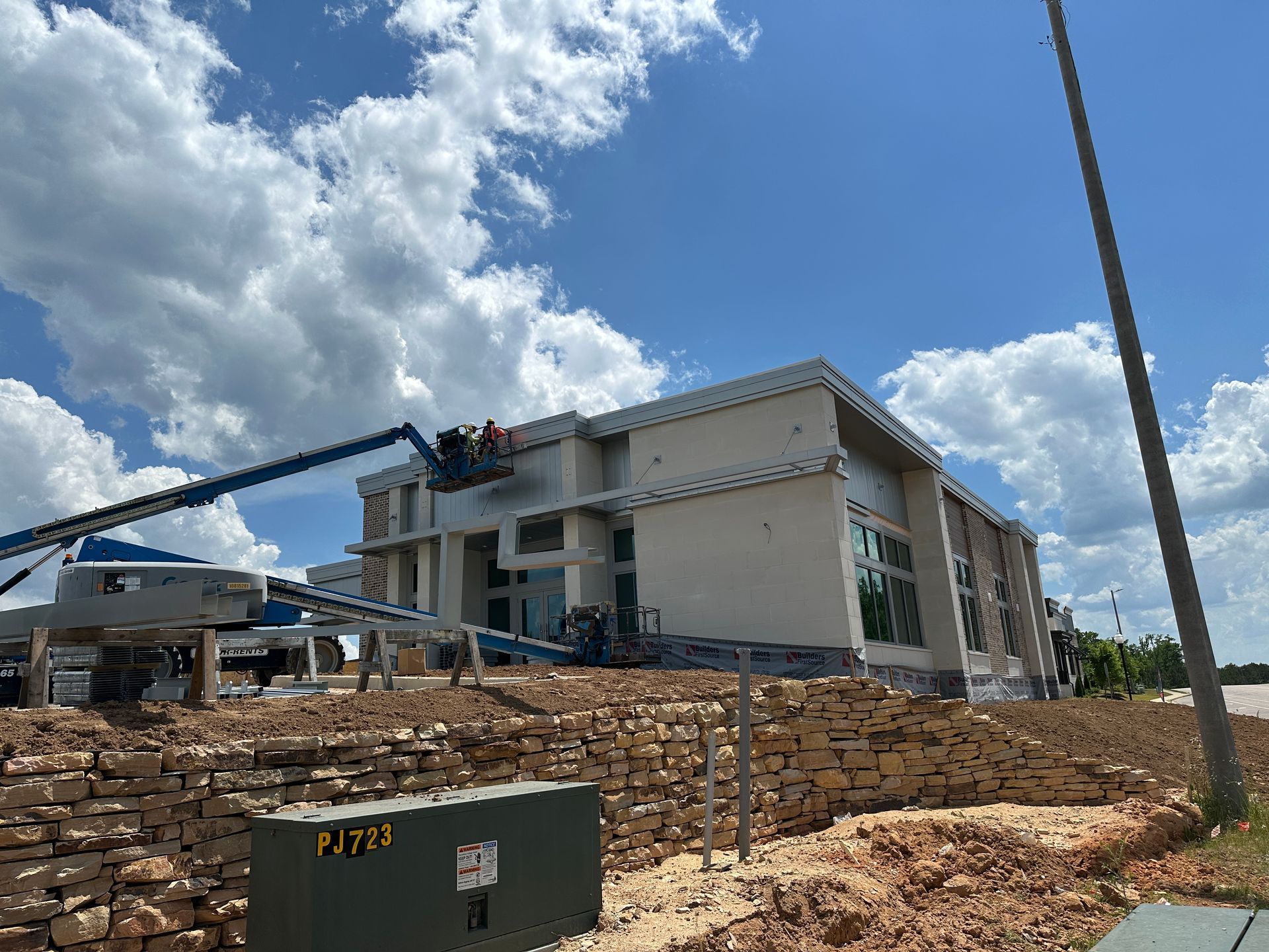 A large building is being built in the middle of a dirt field.