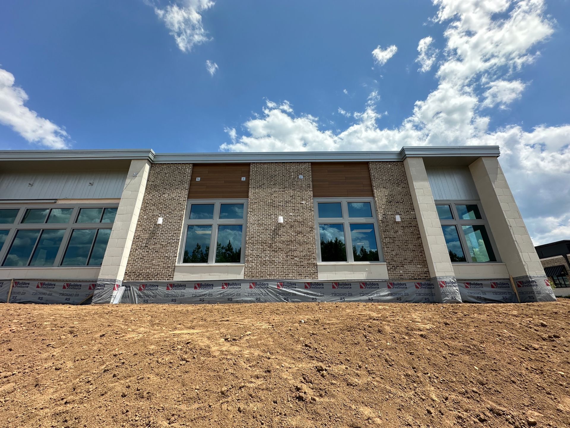 A large building with a lot of windows is sitting on top of a dirt hill.