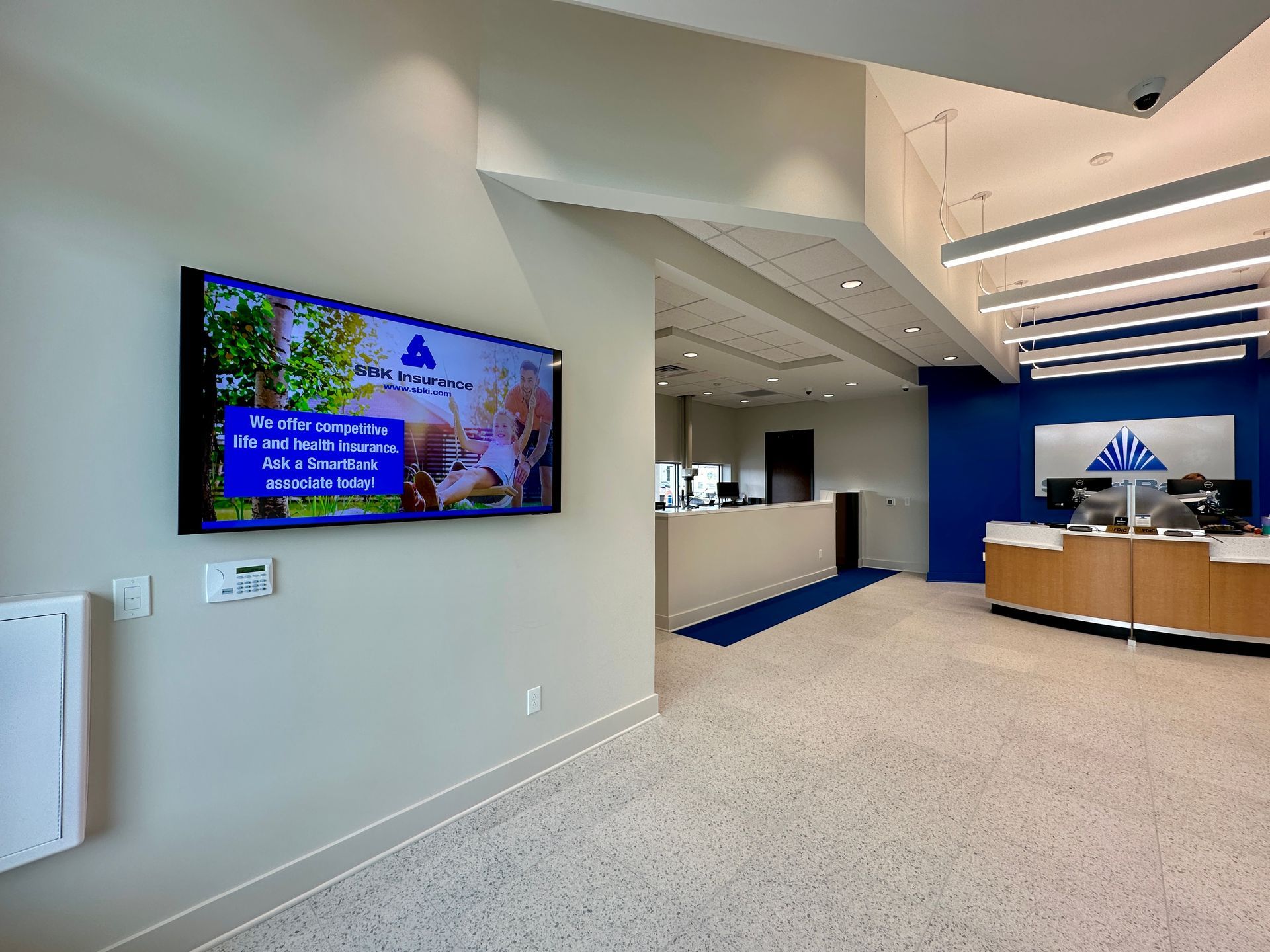 A large flat screen tv is hanging on a wall in a lobby.