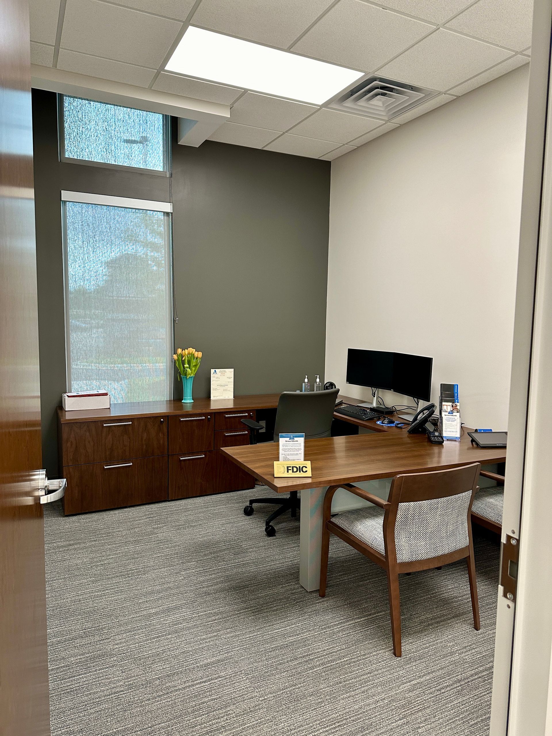 A small office with a desk , chairs and a computer.