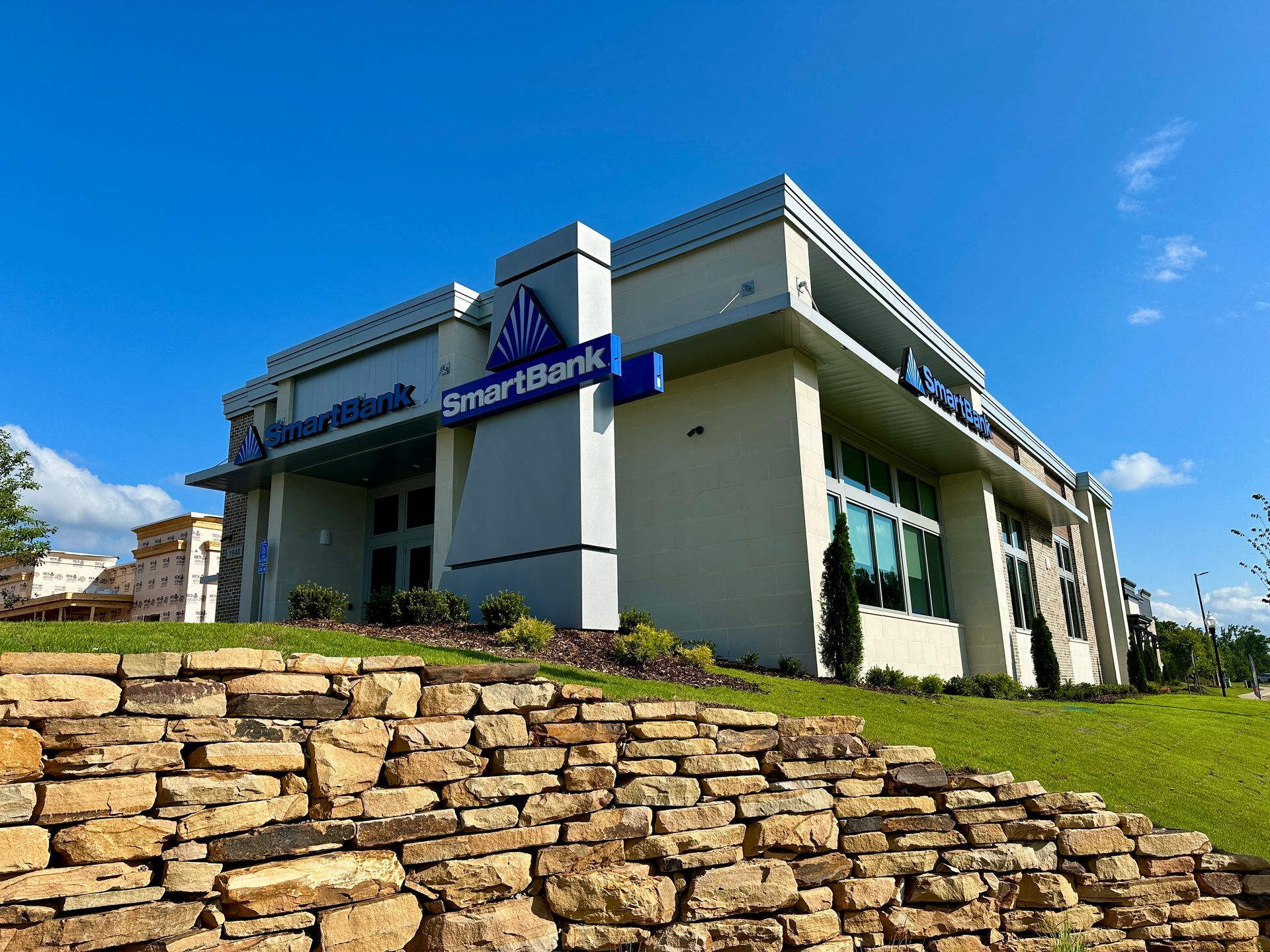 A smart bank building with a stone wall in front of it.