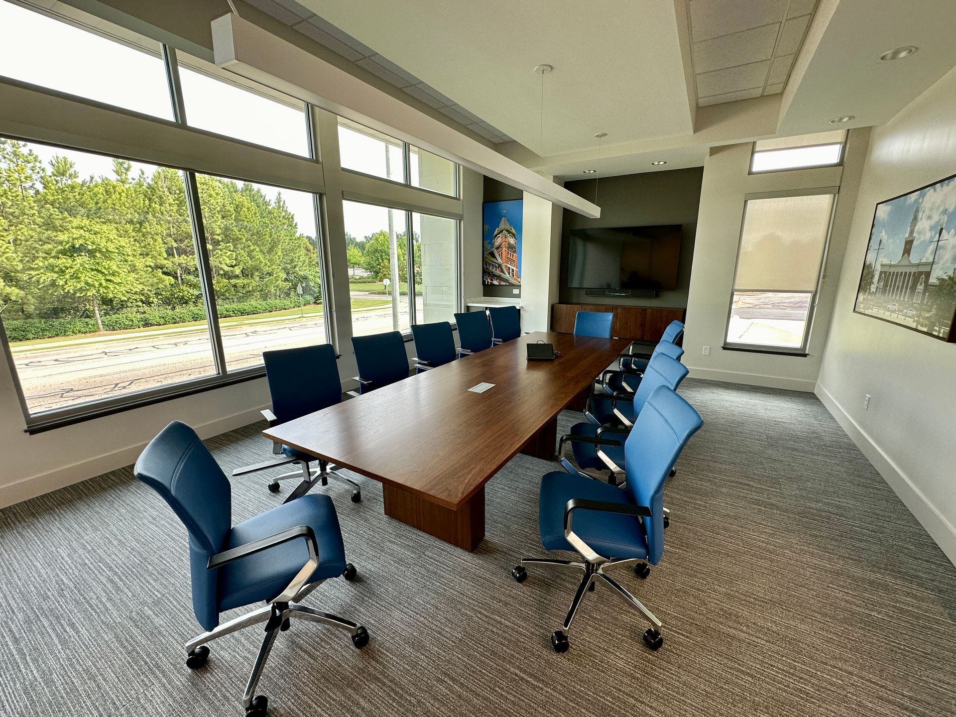 A conference room with a long table and blue chairs.