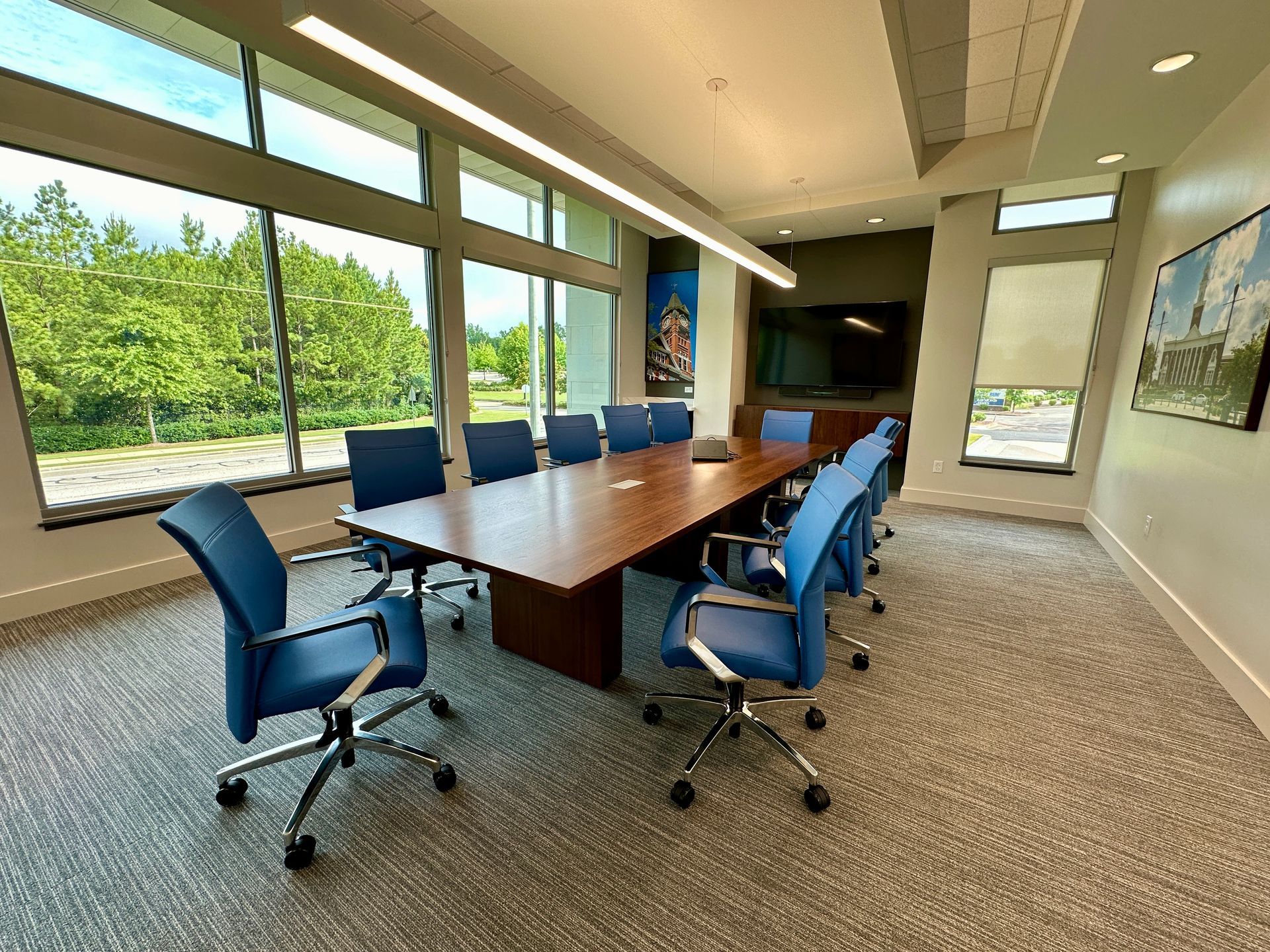 A conference room with a long table and blue chairs.