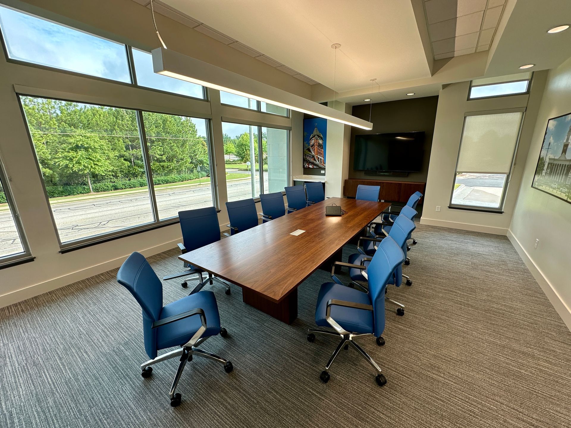 A conference room with a long wooden table and blue chairs.