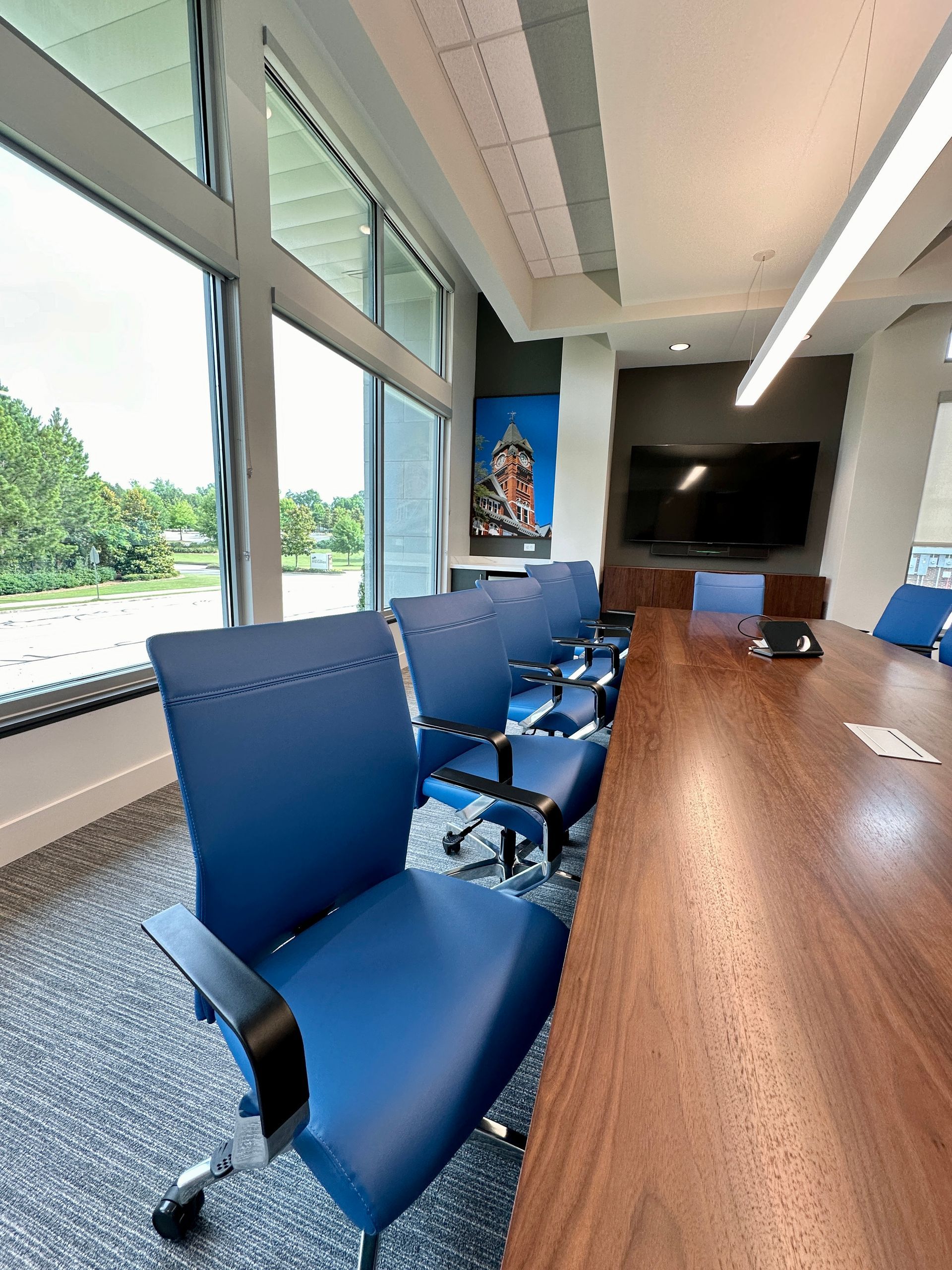 A conference room with a long table and blue chairs
