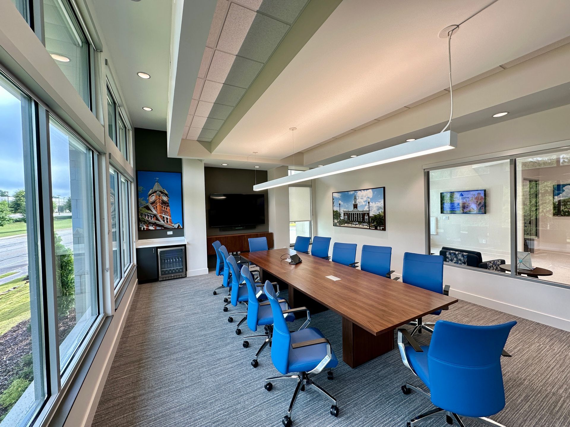 A conference room with a long table and blue chairs.