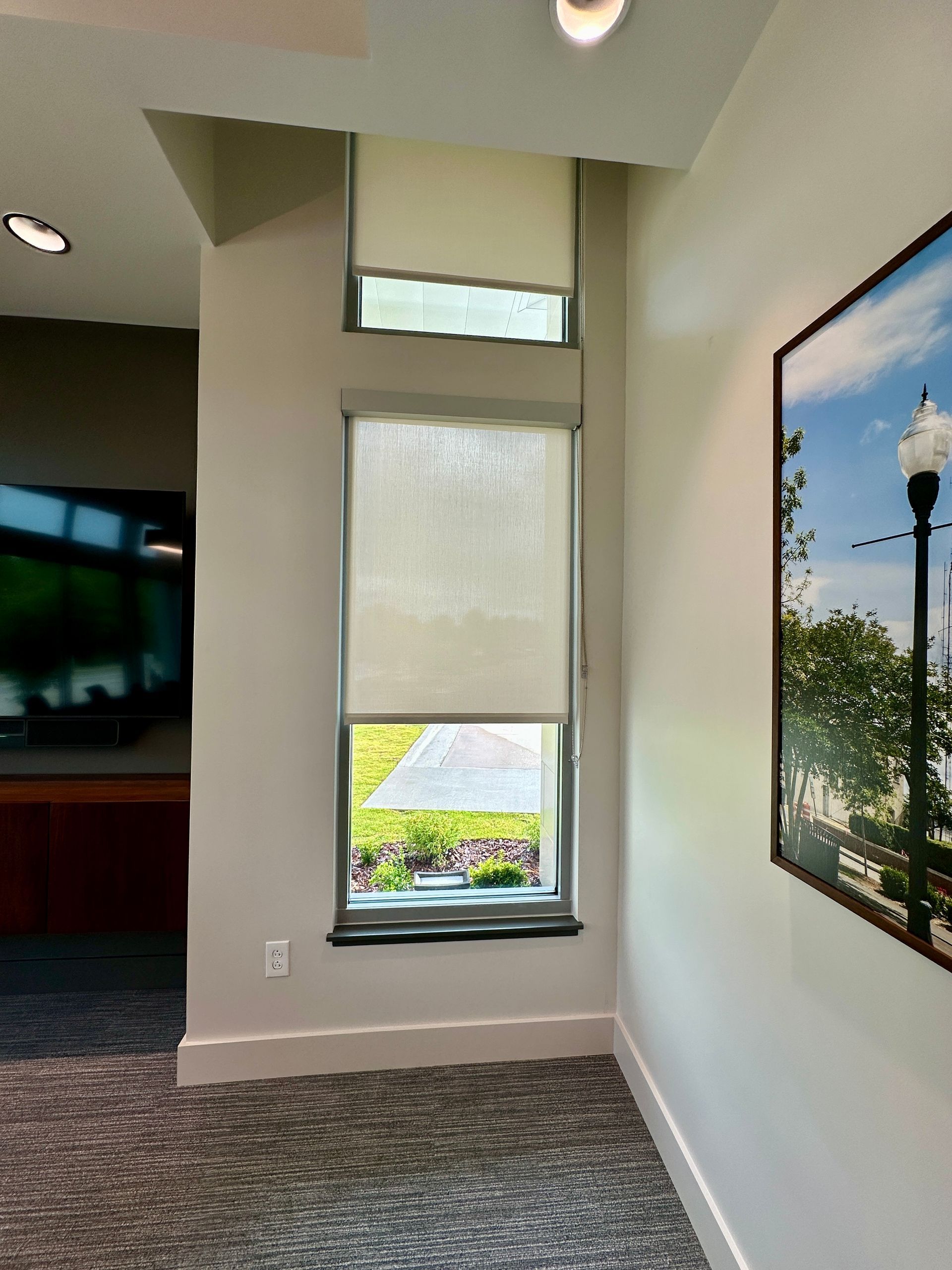 A room with a large window and a picture on the wall.