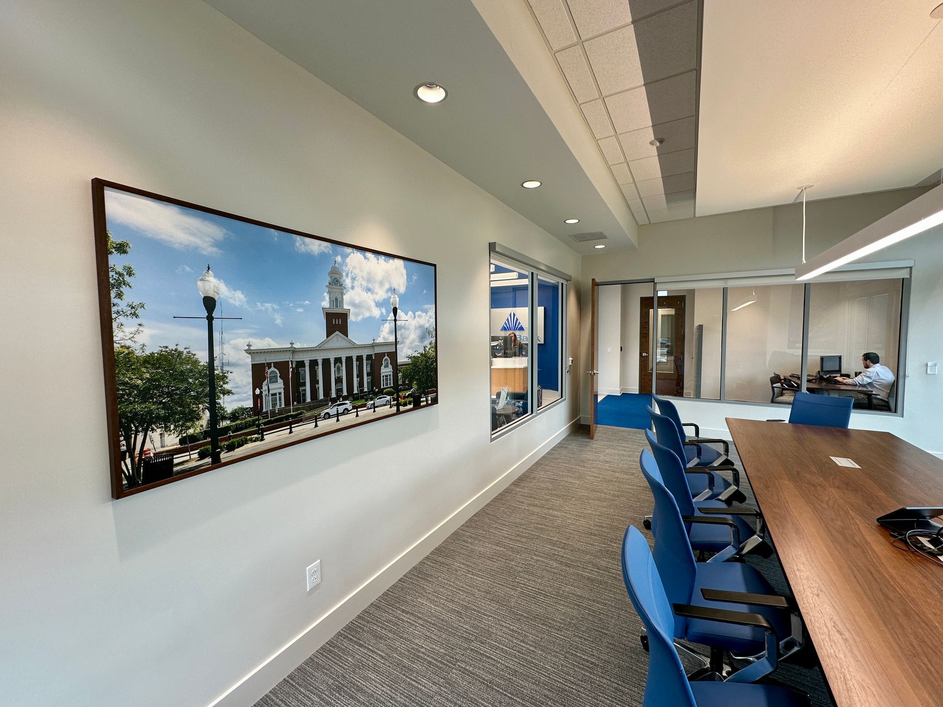 A conference room with a long table and chairs and a large picture on the wall.