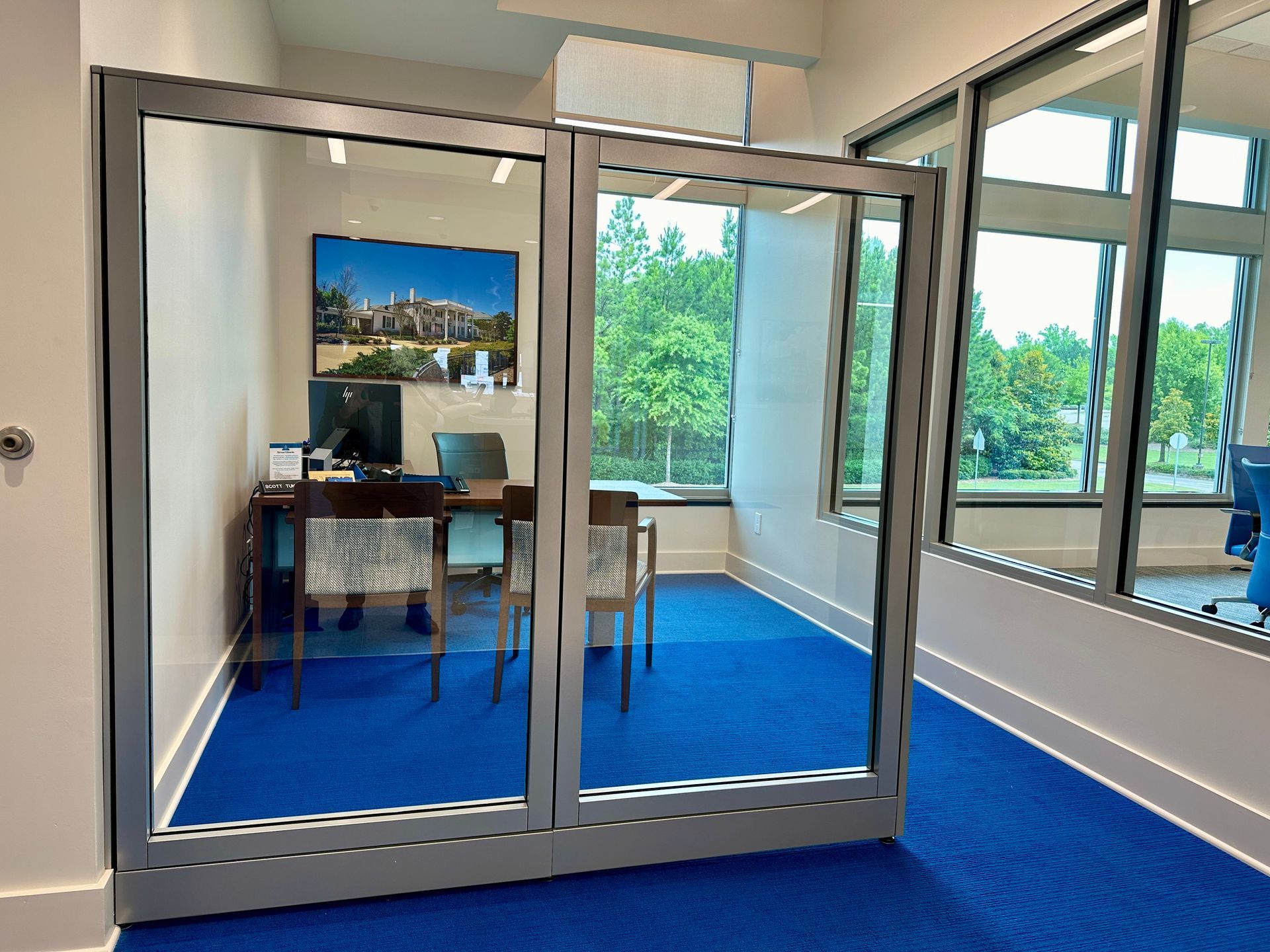 A room with a blue carpet and a desk with a computer on it.